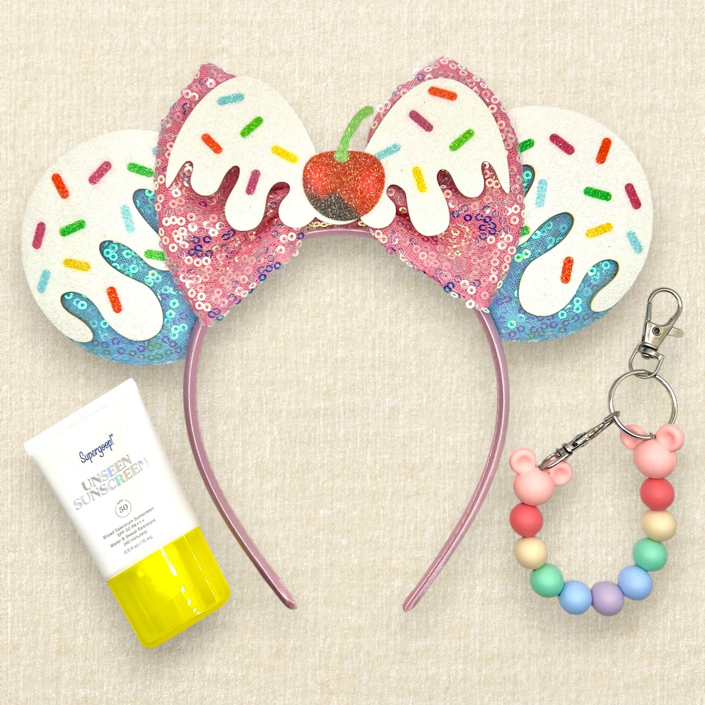 Colorful blue and pink ice cream-themed headband with sprinkles and cherry; small sunscreen; colorful beaded mouse ears holder