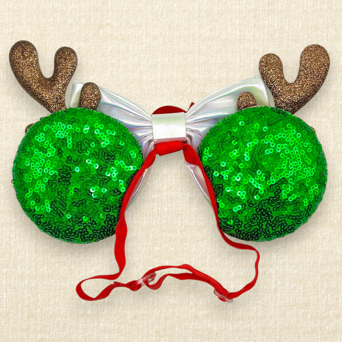 Christmas-themed elastic mouse ears headband with glittery reindeer antlers, red and green peppermint candy cane swirl, an iridescent white bow, and a red spiral candy center on a beige textured background. (Back view)