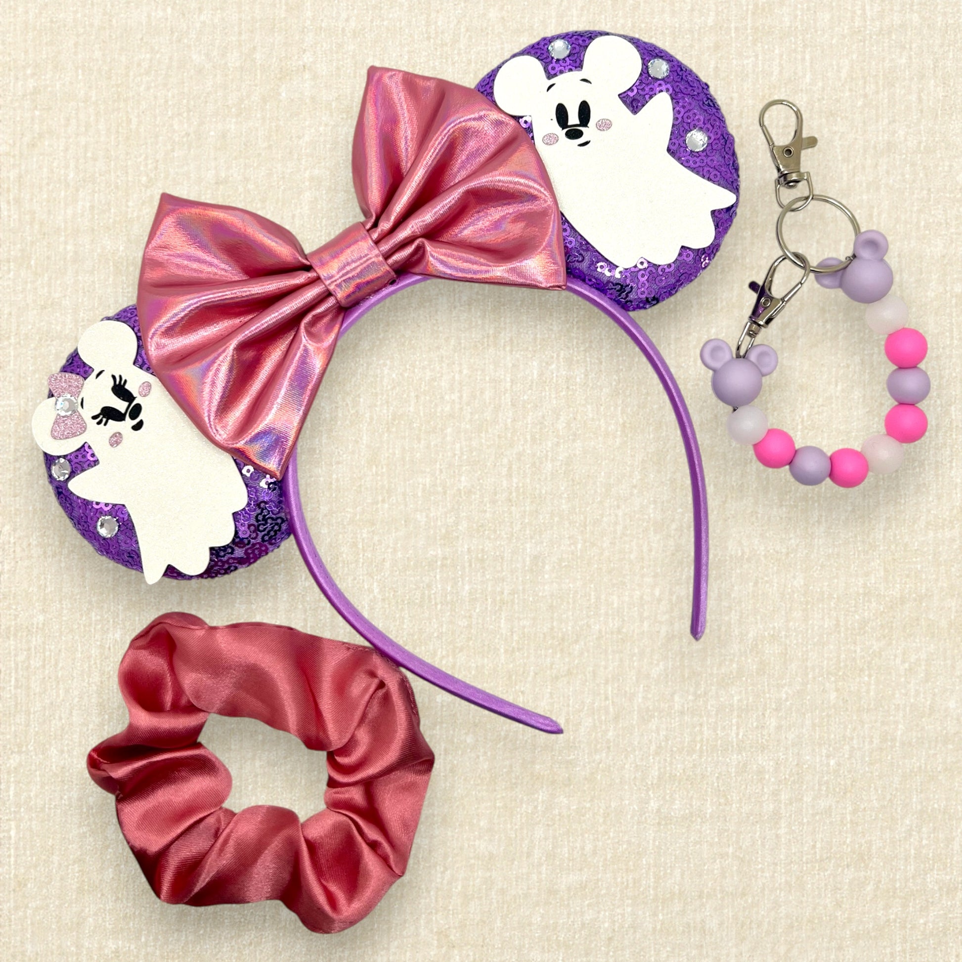 Purple sequin mouse ears with iridescent pink bow and Mickey and Minnie ghosts; pink scrunchie; purple and pink beaded mouse ears holder keychain
