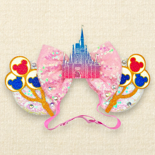 White sequin mouse ears with colorful mouse balloons and a pink bow with pastel pink and blue castle centerpiece on an elastic headband