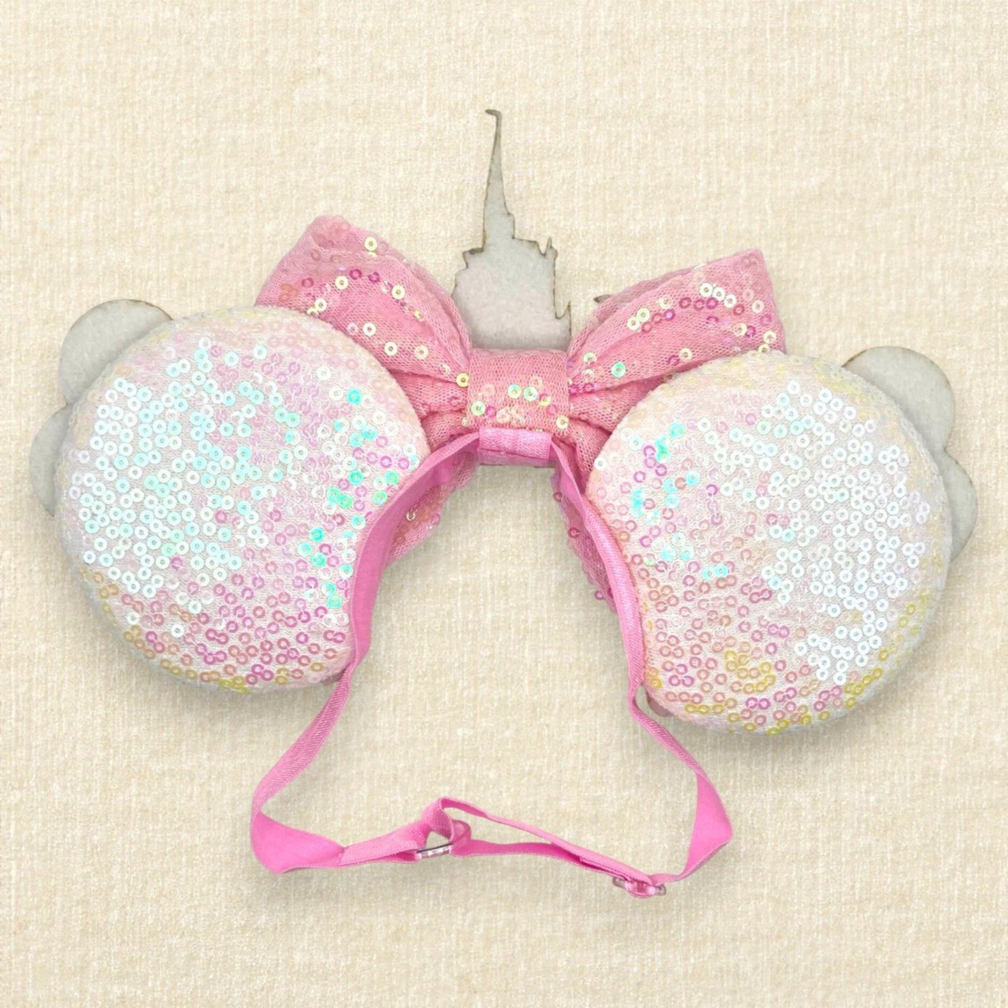 White sequin mouse ears with colorful mouse balloons and a pink bow with pastel pink and blue castle centerpiece on an elastic headband (back view)