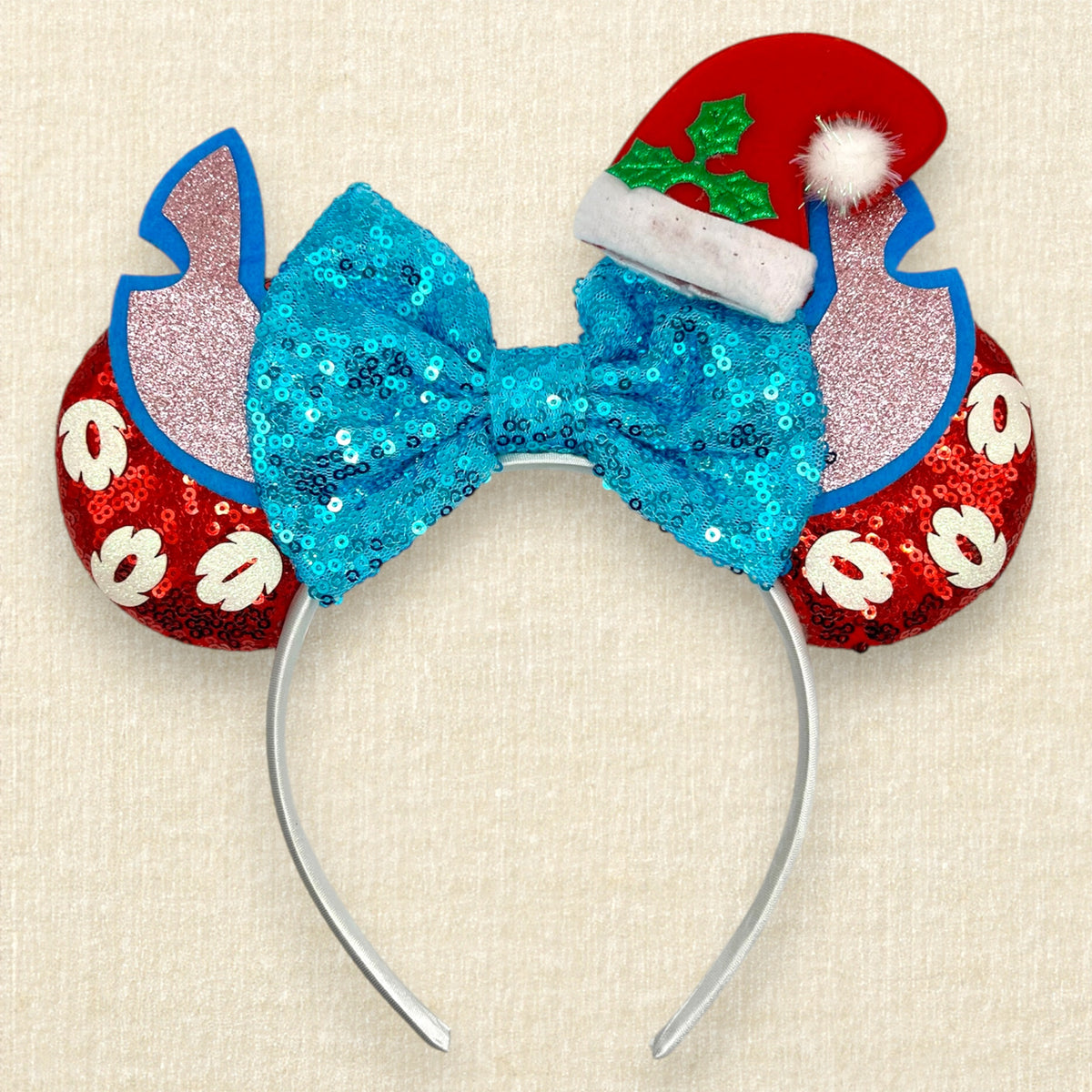 Christmas-themed mouse ears headband featuring a large sequined turquoise bow, red glitter mouse ears with white glitter palm leaves, blue and pink alien ears, and a red Santa hat with green holly.