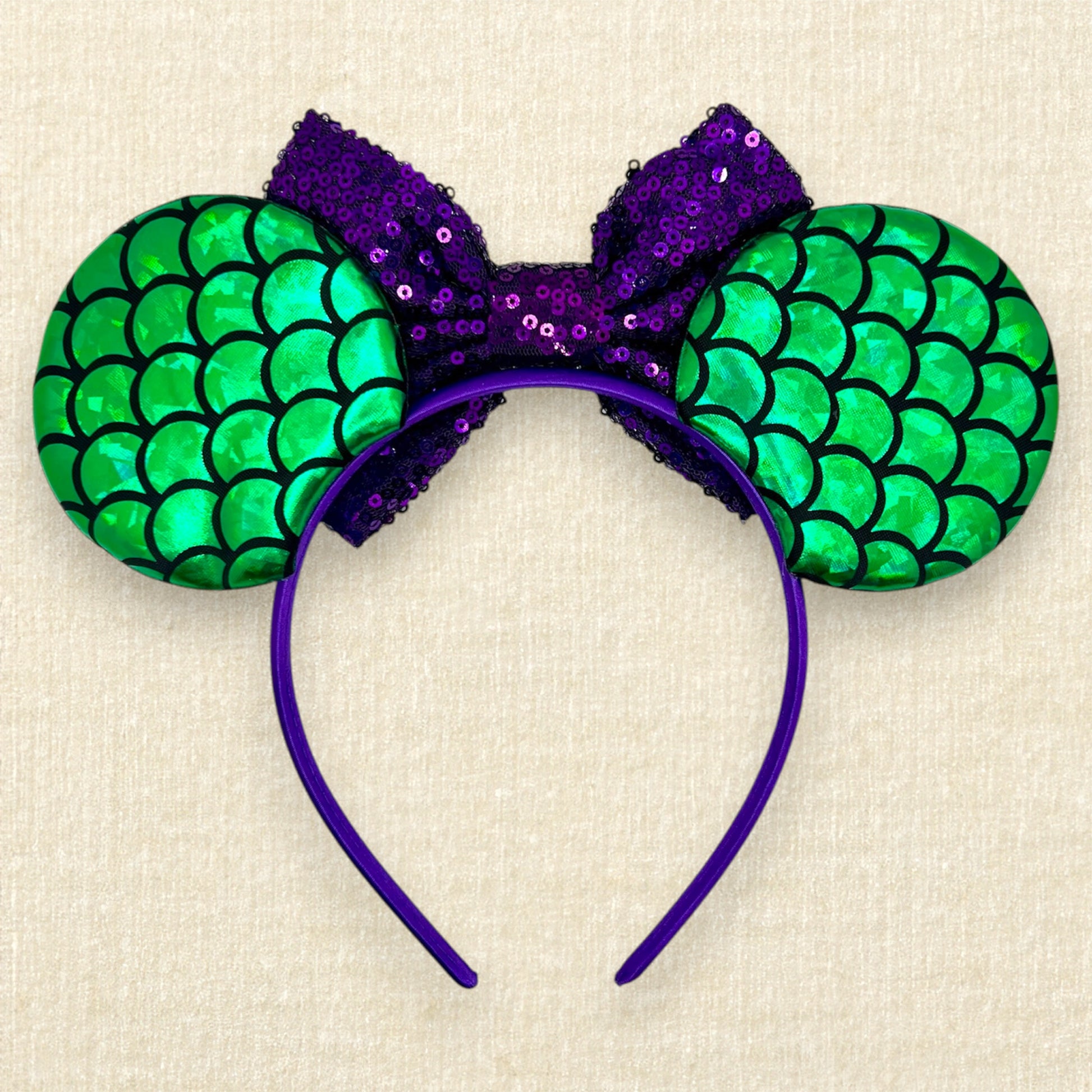 Mouse ears with a green iridescent scale pattern with purple bow, pearls, glitter starfish, and silver fork centerpiece (back view)