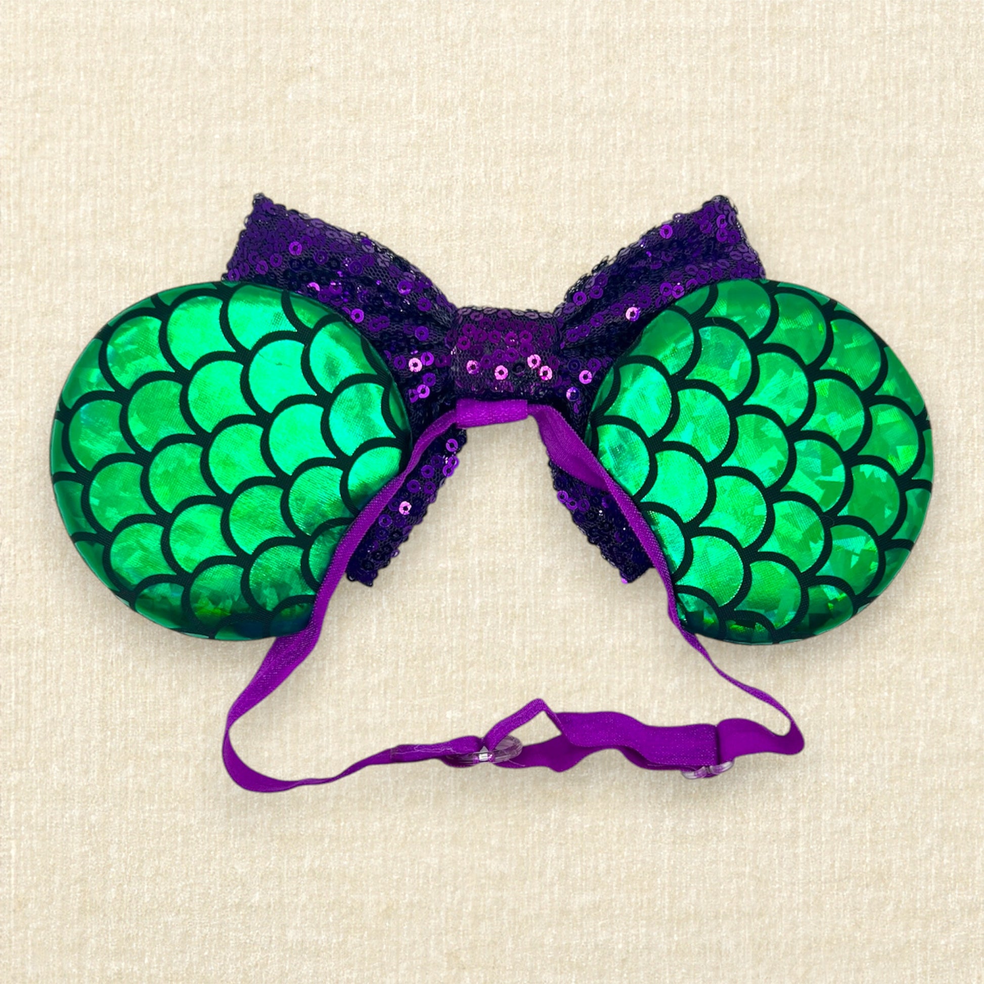 Mouse ears with a green iridescent scale pattern with purple bow, pearls, glitter starfish, and silver fork on an elastic headband