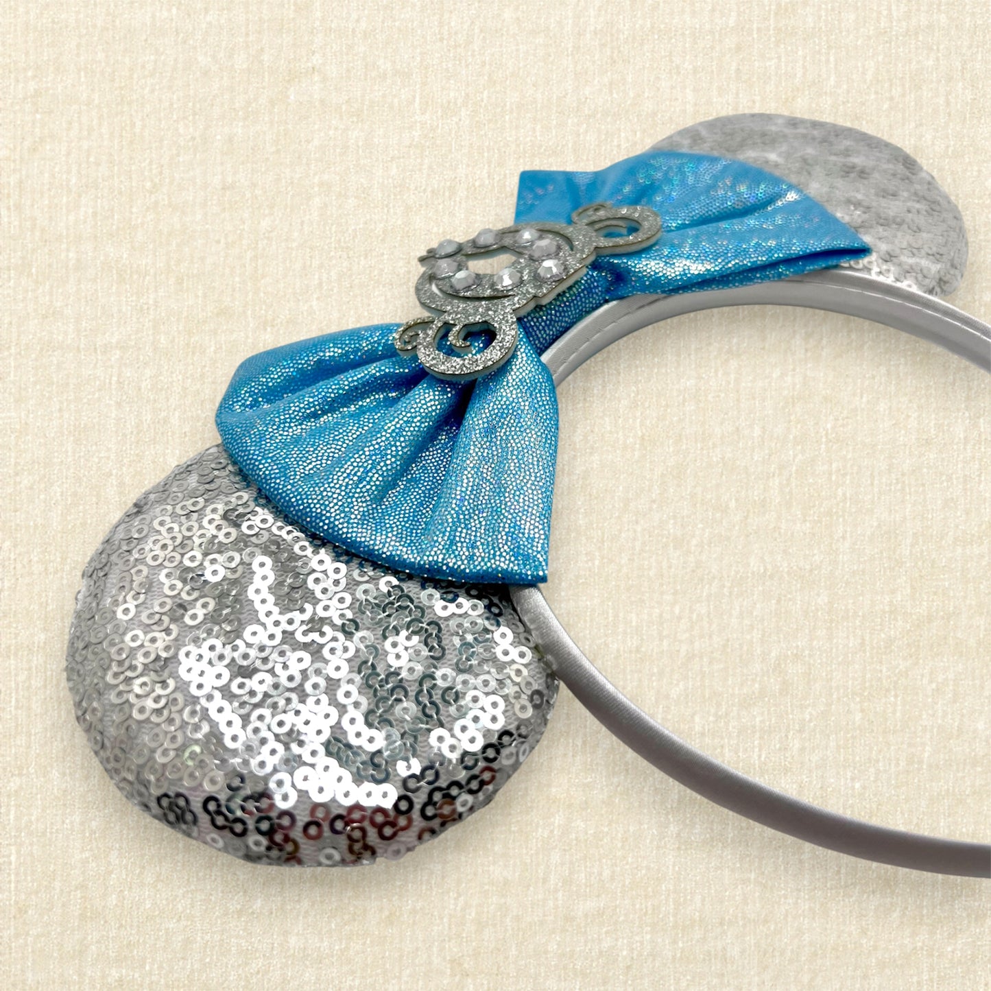Silver sequin mouse ears with shimmery blue bow, silver glitter carriage accent, and rhinestones