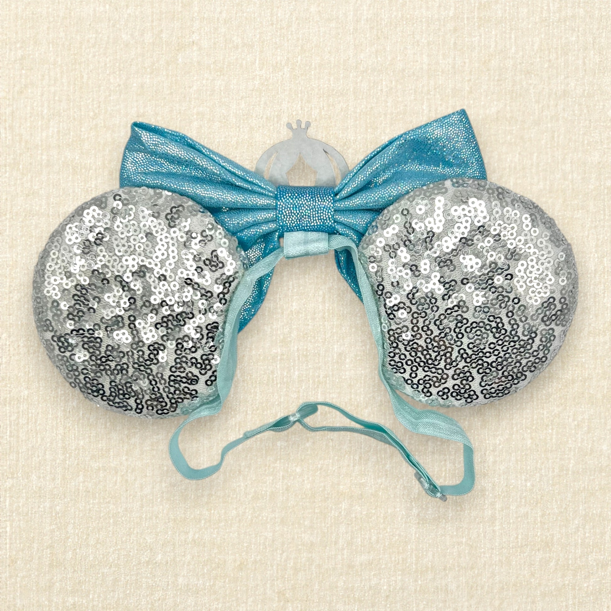 Silver sequin mouse ears on an elastic headband with shimmery blue bow and silver glitter carriage accent and rhinestones