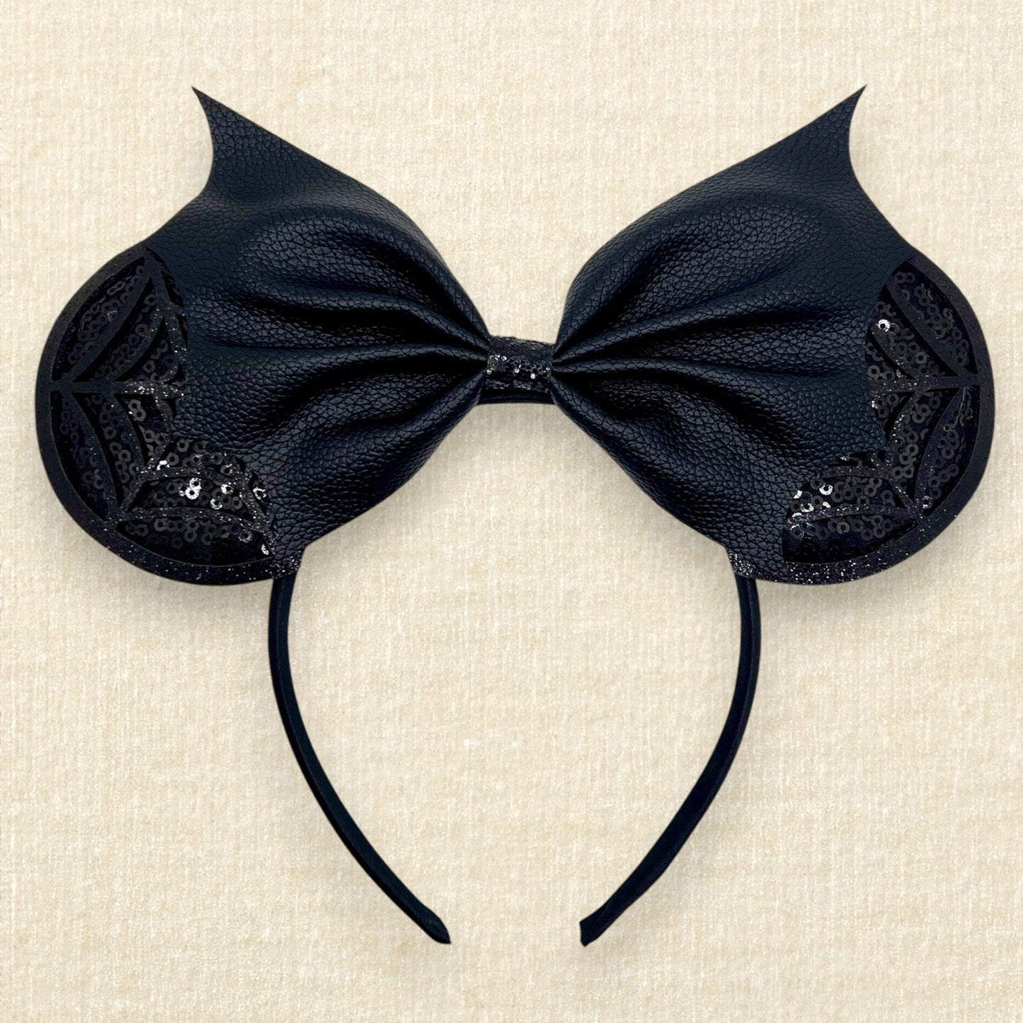 Halloween-themed mouse ears headband with black sequin ears, black glitter cobwebs, and black bat wing faux leather bow