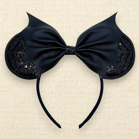 Halloween-themed mouse ears headband with black sequin ears, black glitter cobwebs, and black bat wing faux leather bow