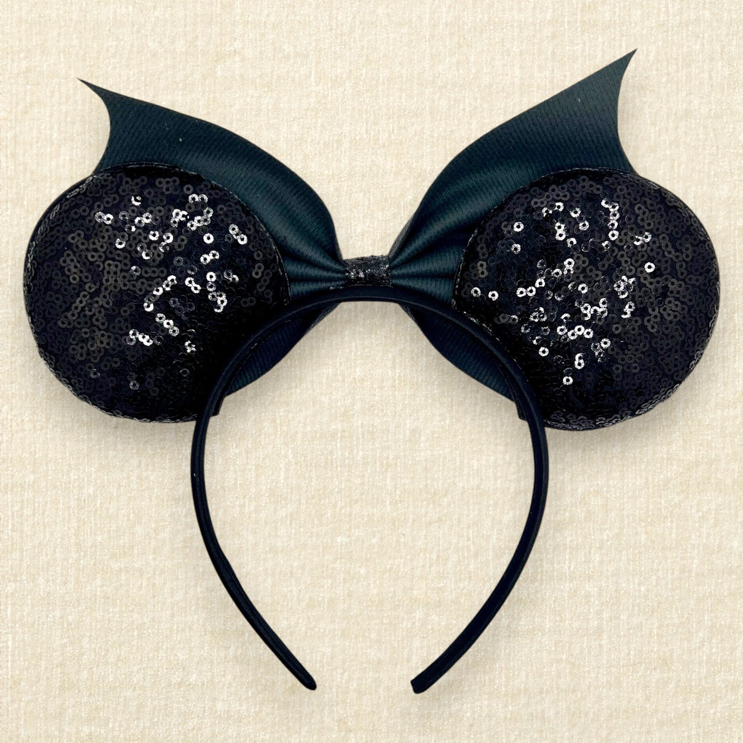 Halloween-themed mouse ears headband with black sequin ears, black glitter cobwebs, and black bat wing faux leather bow (back view)