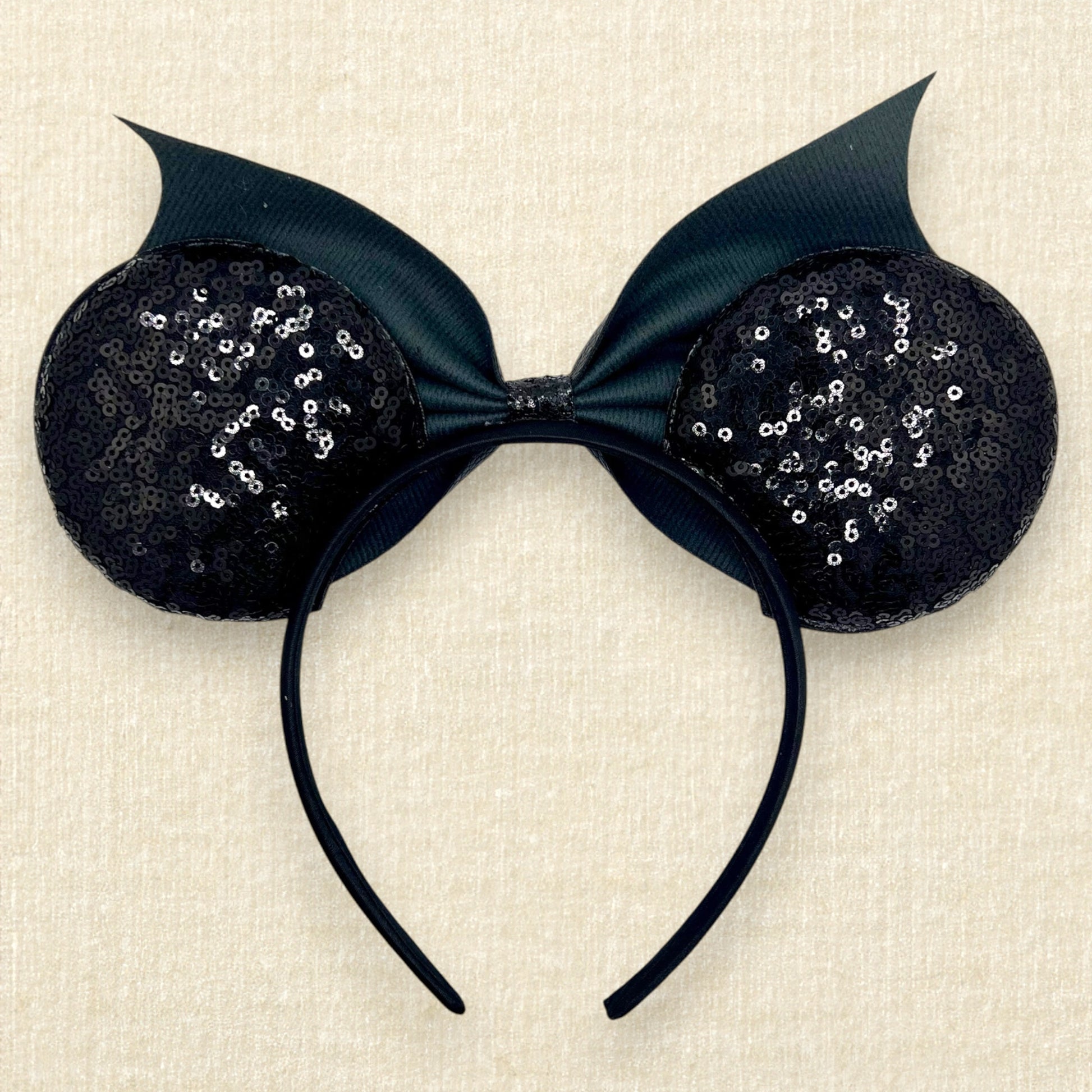 Halloween-themed mouse ears headband with black sequin ears, black glitter cobwebs, and black bat wing faux leather bow (back view)