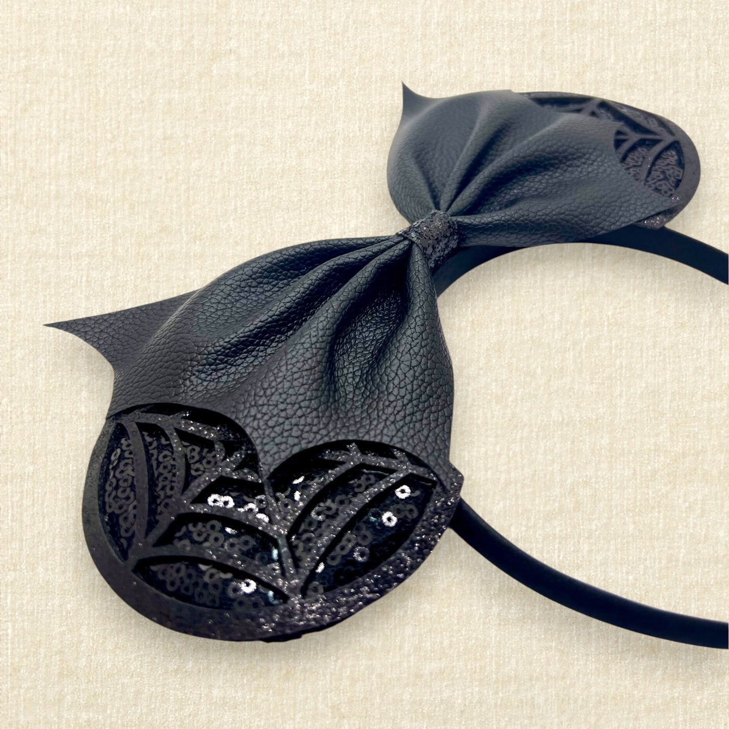 Halloween-themed mouse ears headband with black sequin ears, black glitter cobwebs, and black bat wing faux leather bow