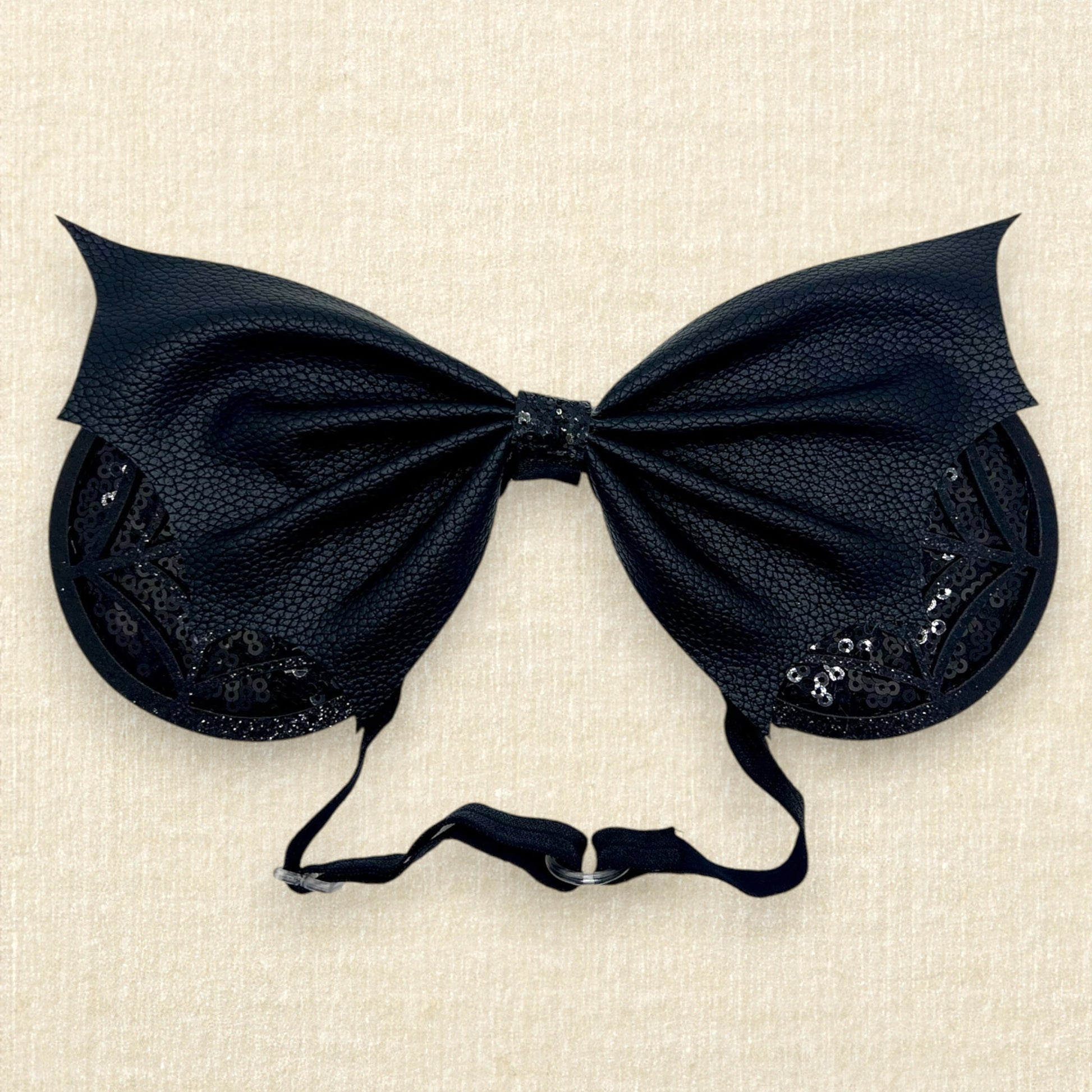 Halloween-themed mouse ears with black sequin ears, black glitter cobwebs, and black faux leather bat wing bow on an elastic headband