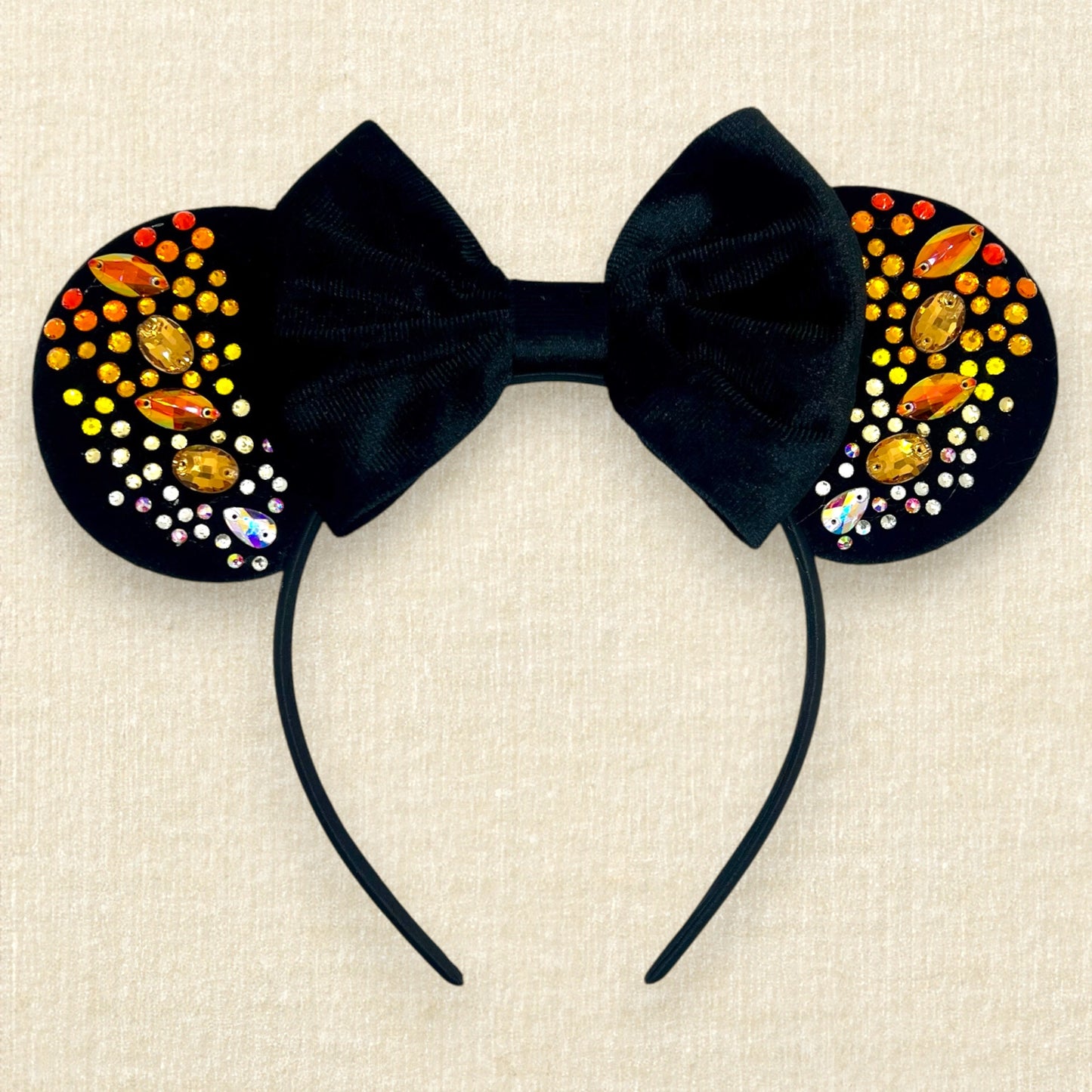 Black velvet mouse ears with black velvet bow and colorful rhinestones in a red, orange, yellow, and crystal ombre gradient pattern