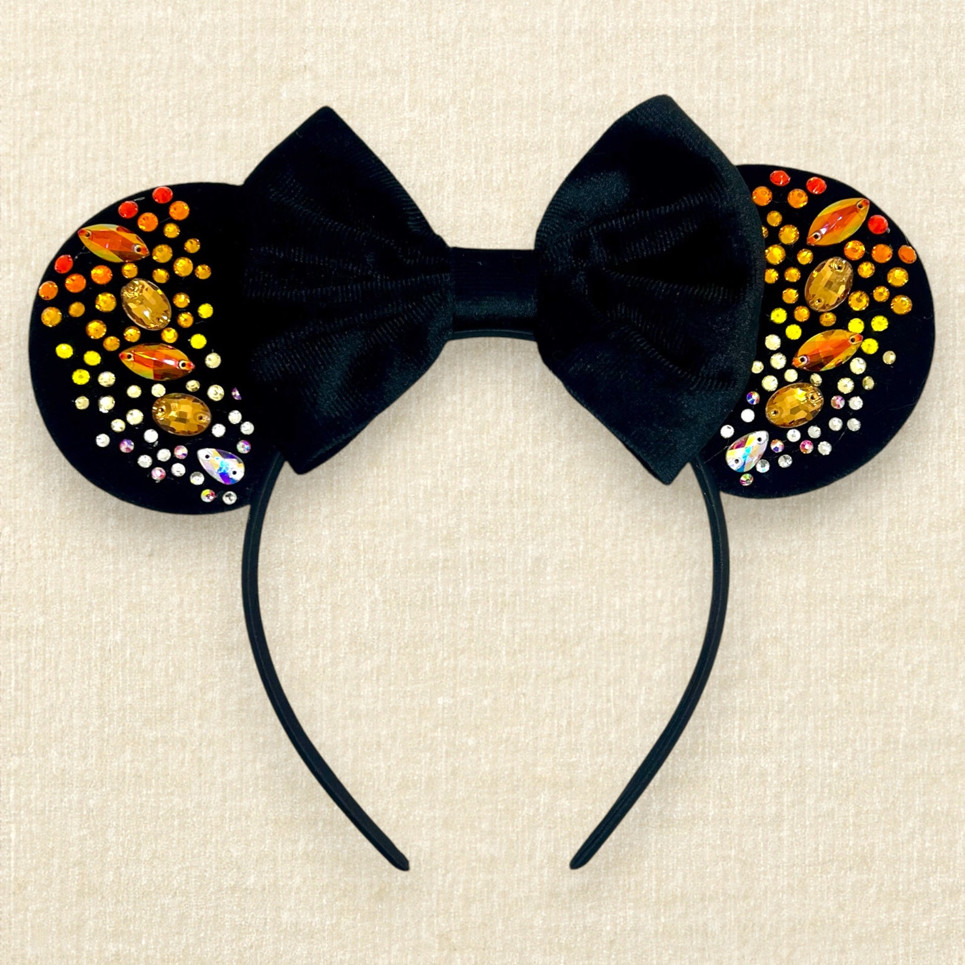 Black velvet mouse ears with black velvet bow and colorful rhinestones in a red, orange, yellow, and crystal ombre gradient pattern