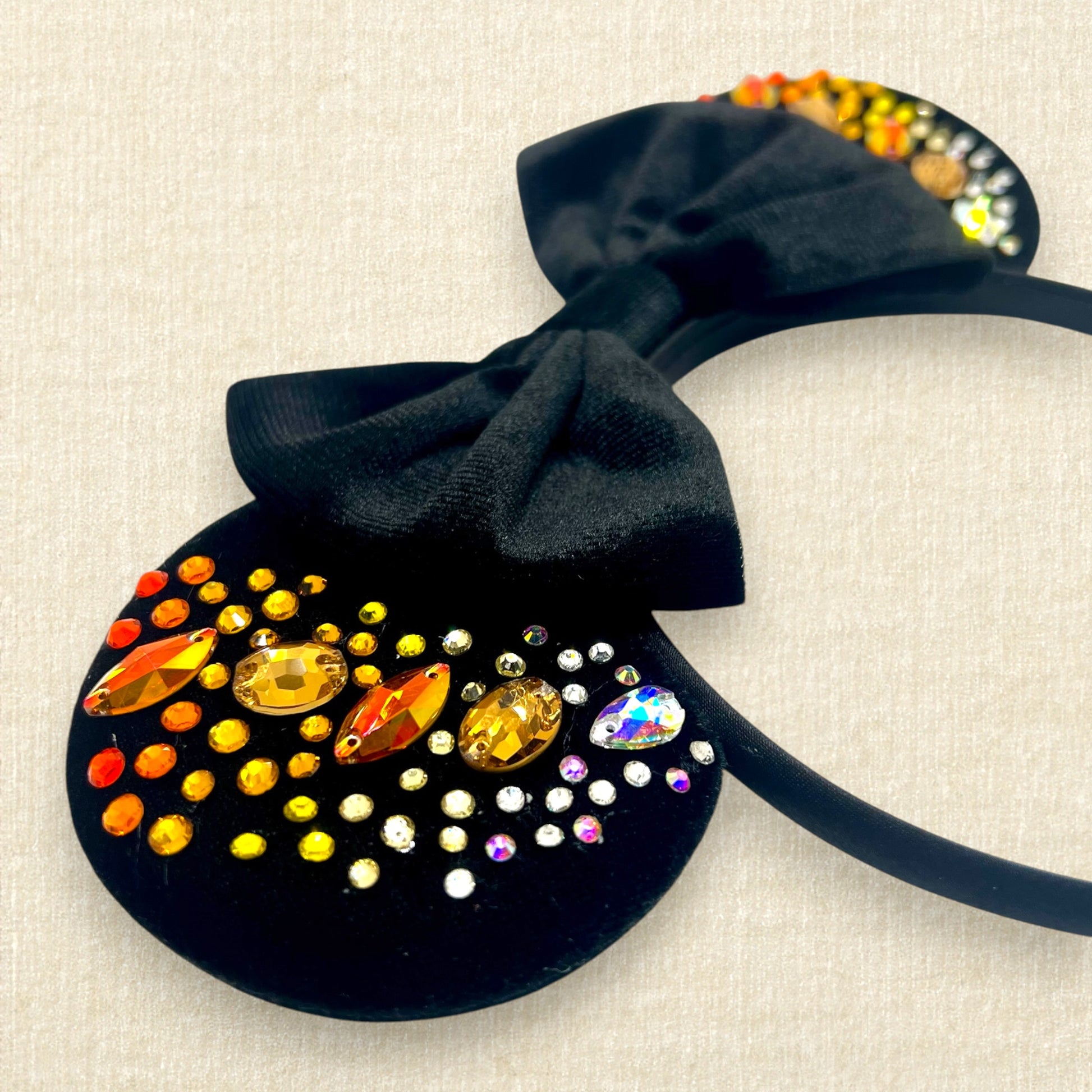 Black velvet mouse ears with black velvet bow and colorful rhinestones in a red, orange, yellow, and crystal ombre gradient pattern