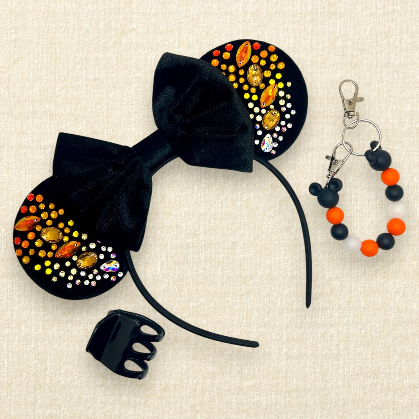 Black velvet mouse ears with black velvet bow and colorful rhinestones in a red, orange, yellow, and crystal ombre gradient pattern; black claw clip; orange and black beaded mouse ears holder keychain