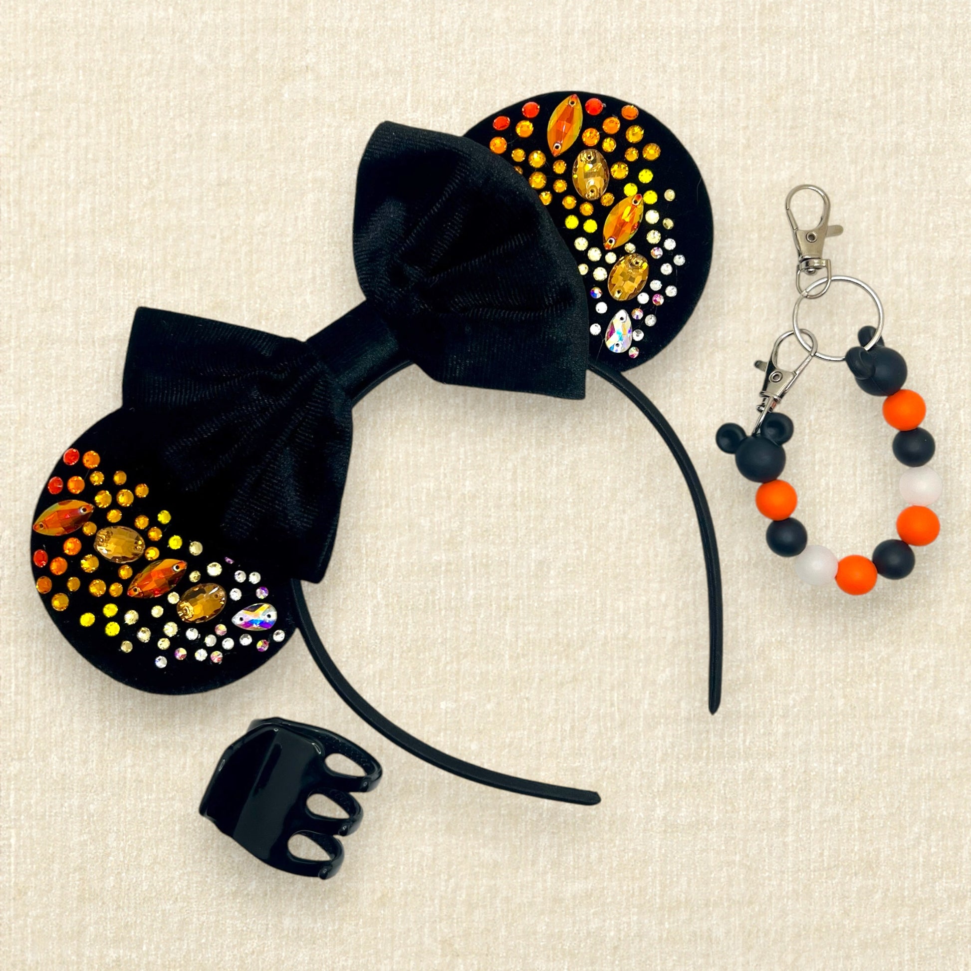 Black velvet mouse ears with black velvet bow and colorful rhinestones in a red, orange, yellow, and crystal ombre gradient pattern; black claw clip; orange and black beaded mouse ears holder keychain