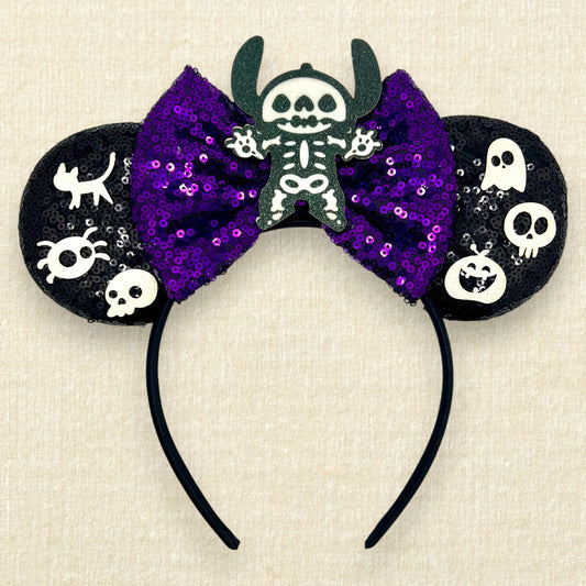 Halloween-themed black mouse ears headband with spooky glitter creatures, purple sequin bow, and skeleton Stitch centerpiece