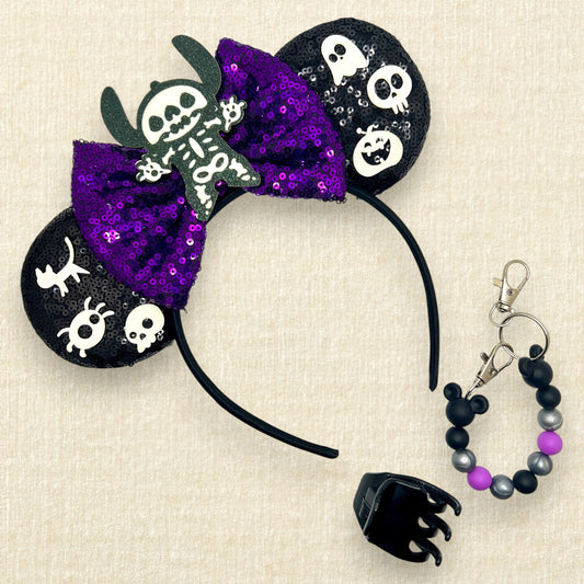 Halloween-themed black mouse ears headband with spooky glitter creatures, purple sequin bow, and skeleton Stitch centerpiece; black claw clip; purple, black, and silver beaded mouse ears holder keychain