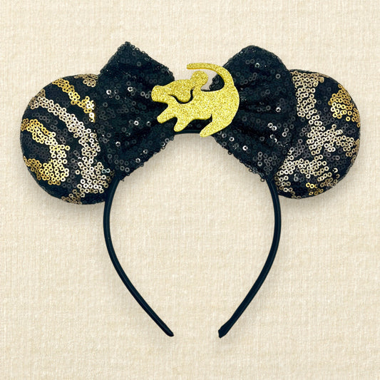 Black and gold sequin mouse ears in a leopard print pattern with a black sequin bow and gold glitter Simba accent