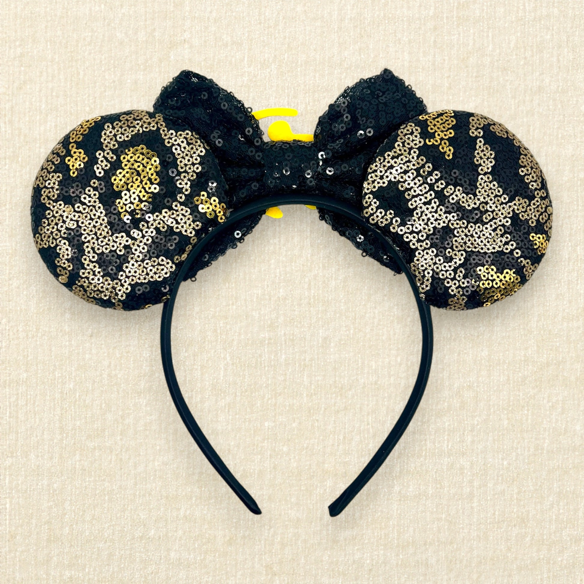 Black and gold sequin mouse ears in a leopard print pattern with a black sequin bow and gold glitter Simba accent