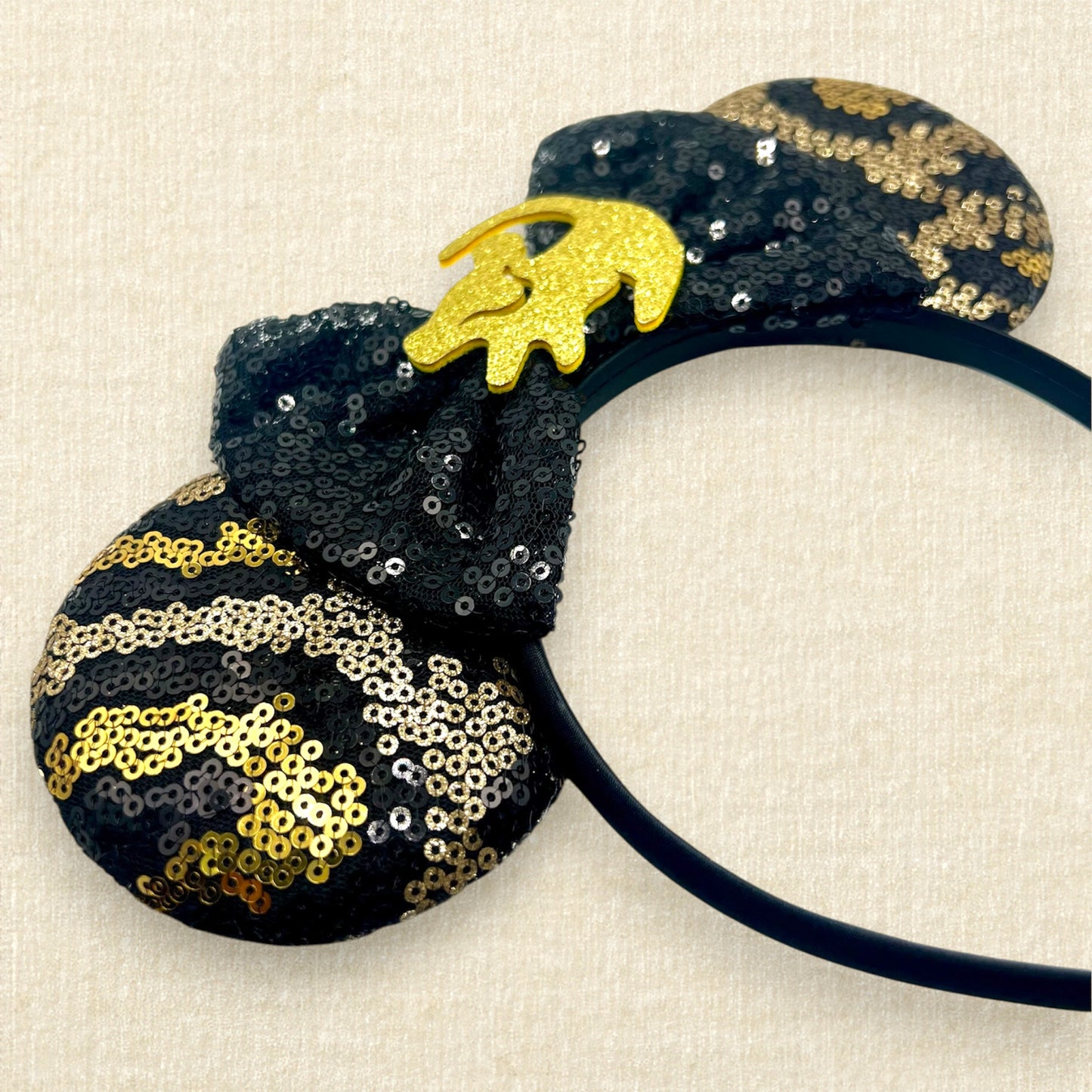 Black and gold sequin mouse ears in a leopard print pattern with a black sequin bow and gold glitter Simba accent