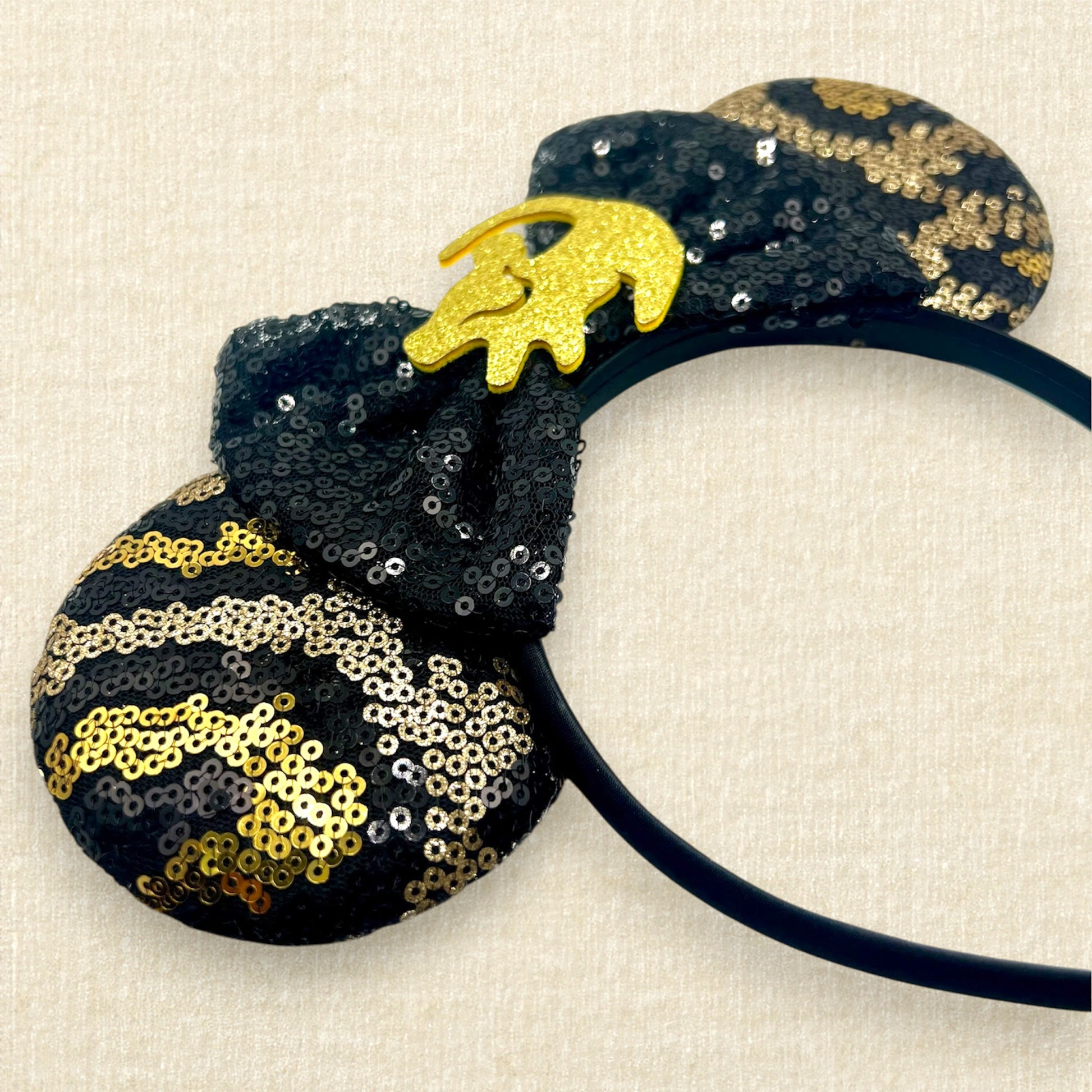 Black and gold sequin mouse ears in a leopard print pattern with a black sequin bow and gold glitter Simba accent