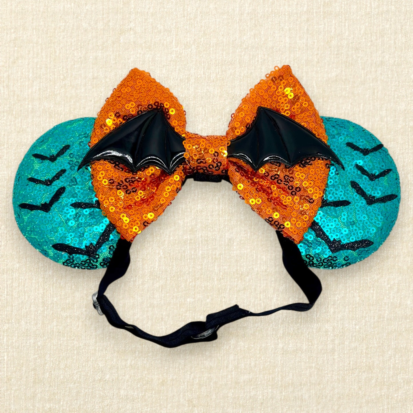 Halloween-themed teal mouse ears with black bats, orange bow, and large bat wings