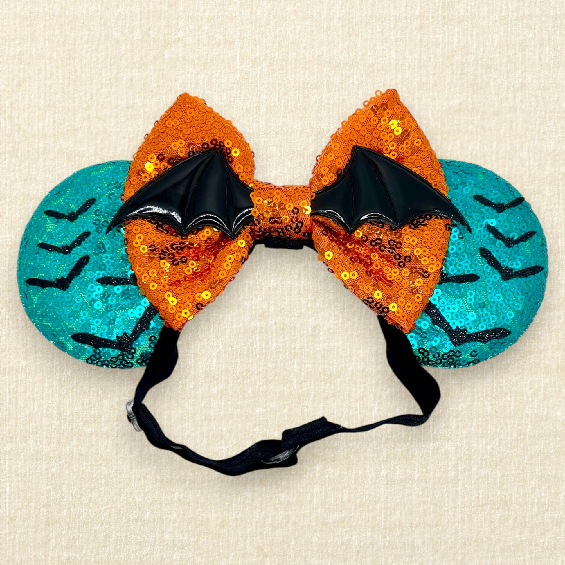 Halloween-themed teal mouse ears with black bats, orange bow, and large bat wings