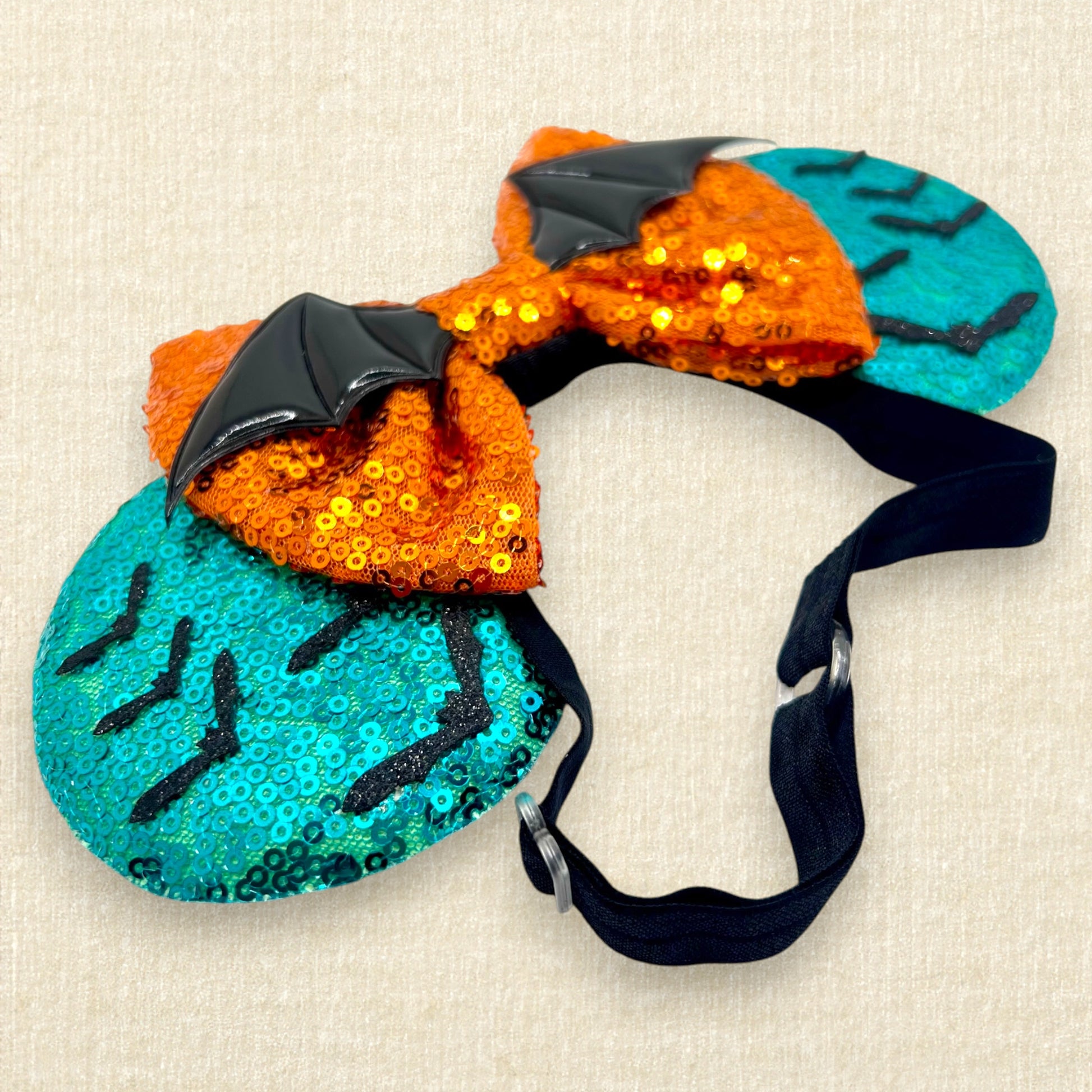 Halloween-themed teal mouse ears with black bats, orange bow, and large bat wings