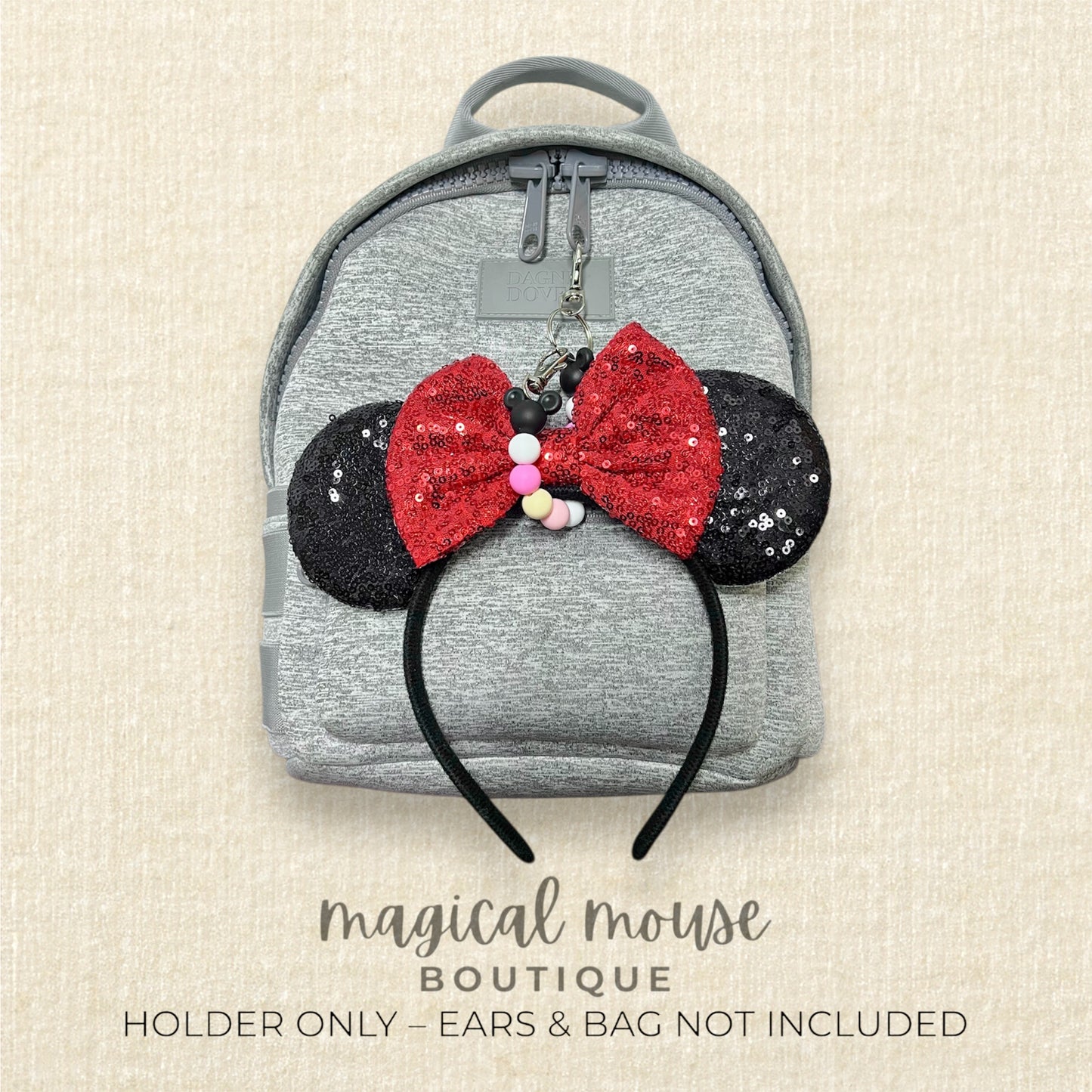 Gray backpack with Minnie Mouse ears keychain on a beige background, featuring 'magical mouse boutique' branding.