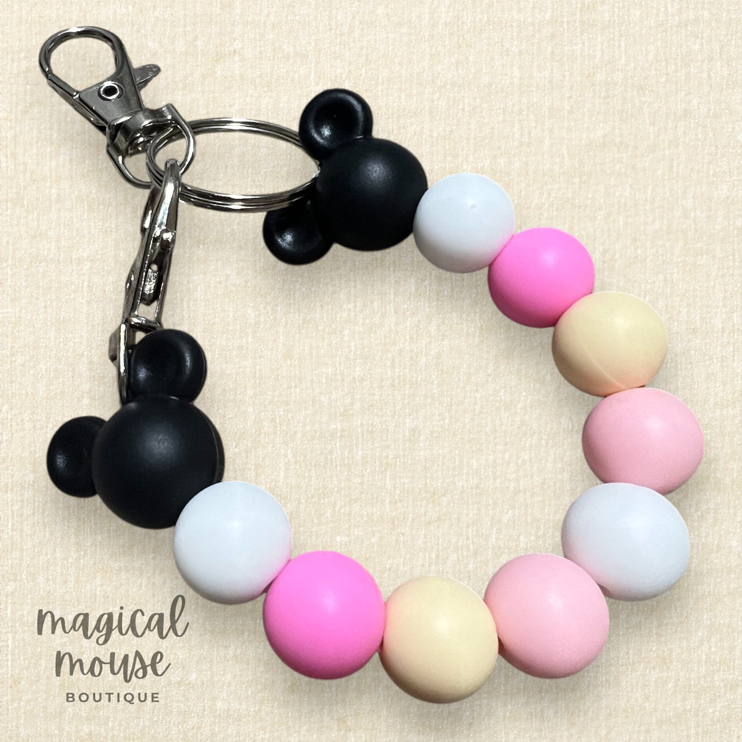 Keychain with colorful pink and white beads and Mickey Mouse ears on a beige background