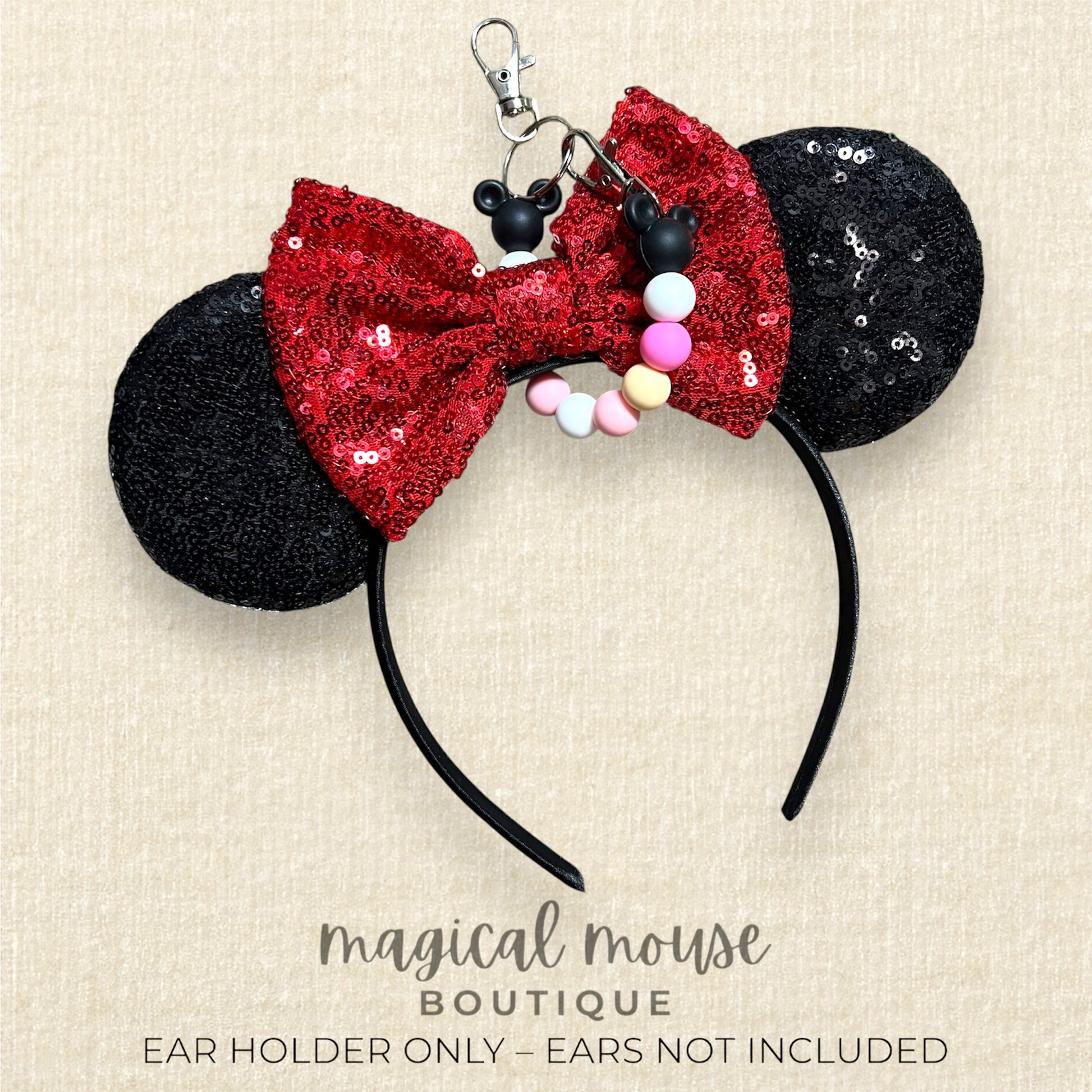 Black and red sequin mouse ears with a bow and beaded mouse ears clip on a beige background, labeled 'magical mouse boutique'.