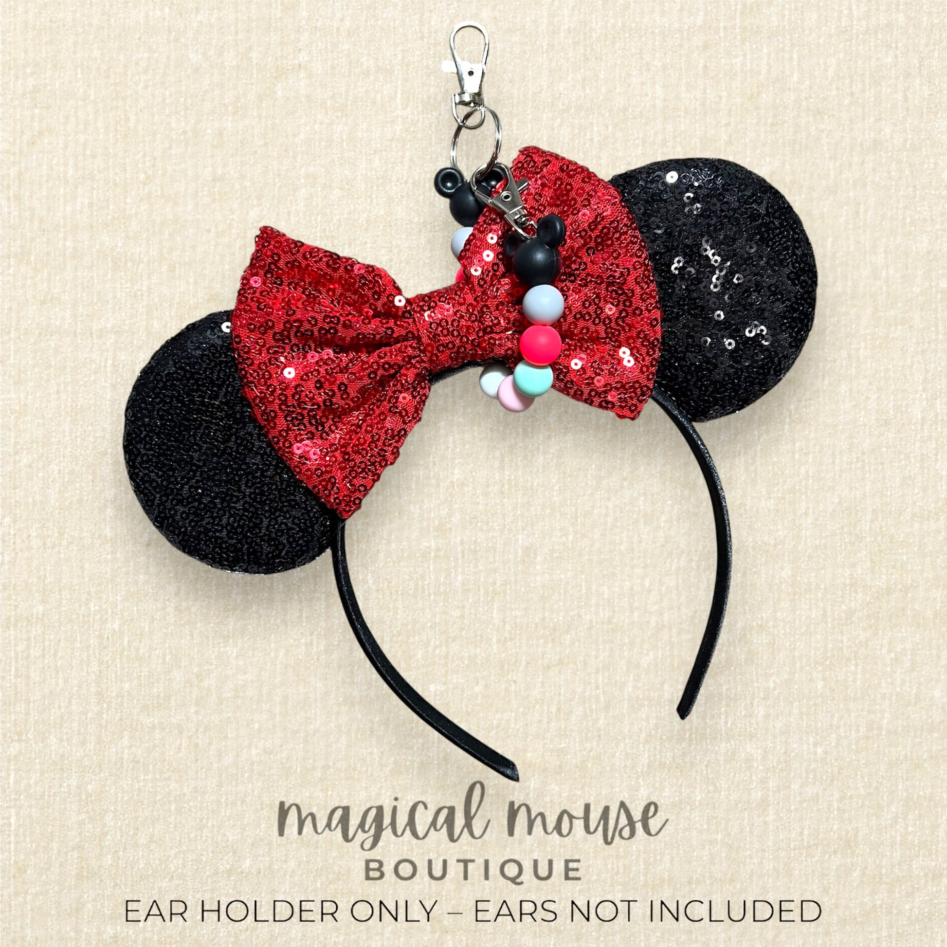 Black and red glittery mouse ears headband with colorful beaded ear clip with 'Magical Mouse Boutique' text on a beige background