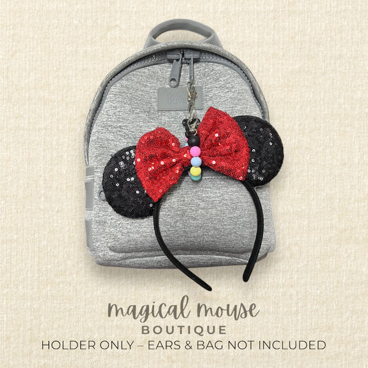 Gray backpack with Minnie Mouse ears and bow keychain on a beige background, brand 'magical mouse boutique' visible.