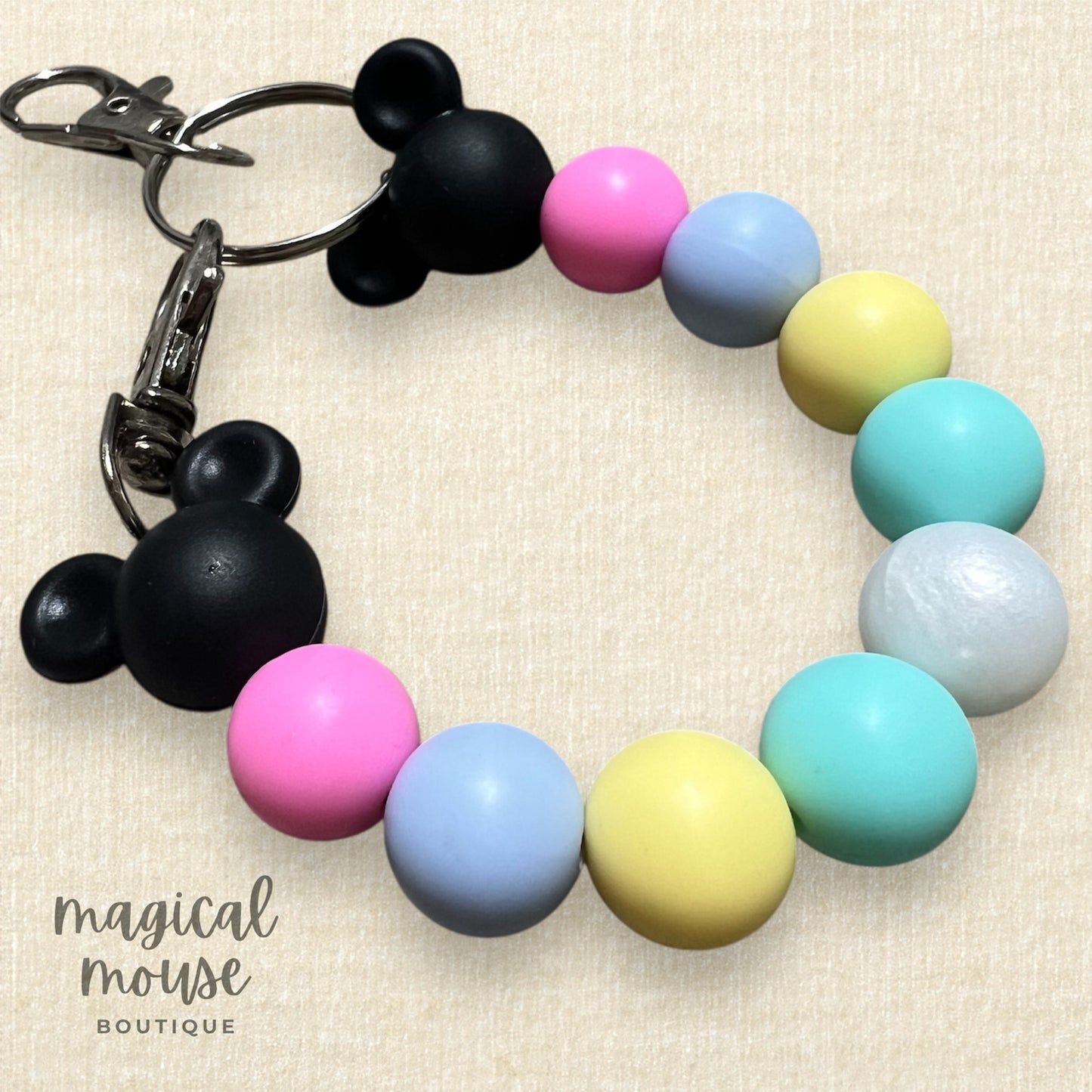 Mouse ears holder clip with colorful beads and Mickey Mouse ears on a beige background