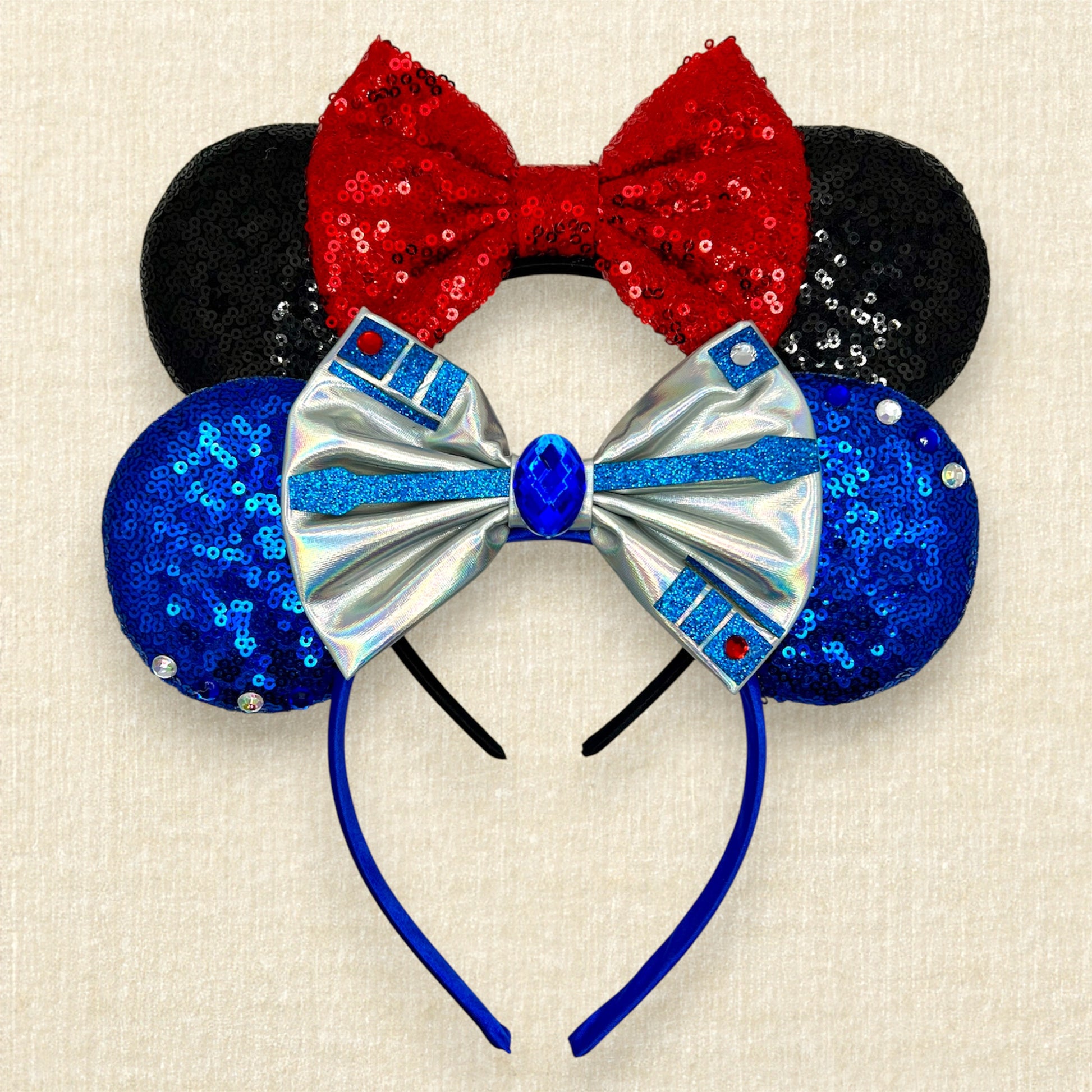 One pair of black mouse ears with red bow, and one pair of blue mouse ears with silver bow, rhinestones, and glitter accents.