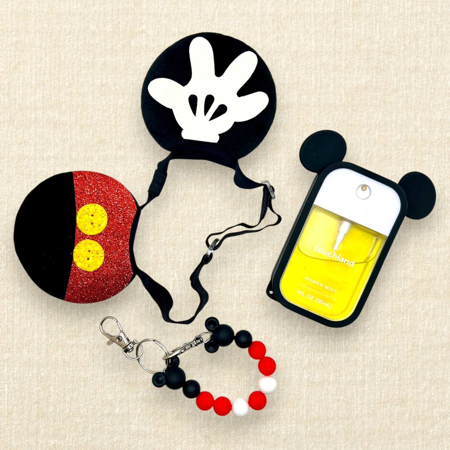 Black velvet bow-free mouse ears on an elastic headband with glitter shorts and glove detail; black and red beaded mouse ears holder keychain; hand sanitizer spray in a black mouse ears case