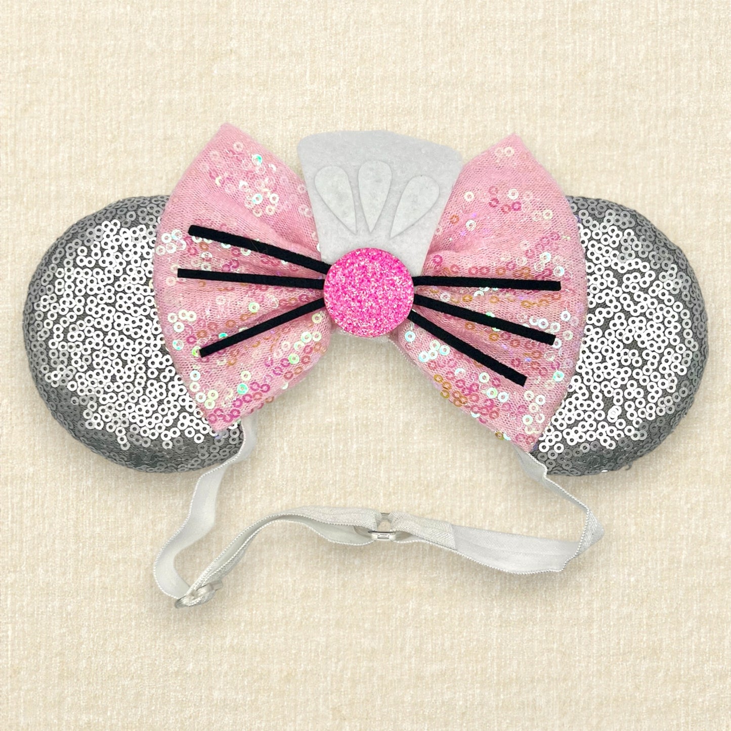 Silver mouse ears with pink sequin bow, mini white chef's hat, and pink glitter mouse nose with whiskers on an elastic headband