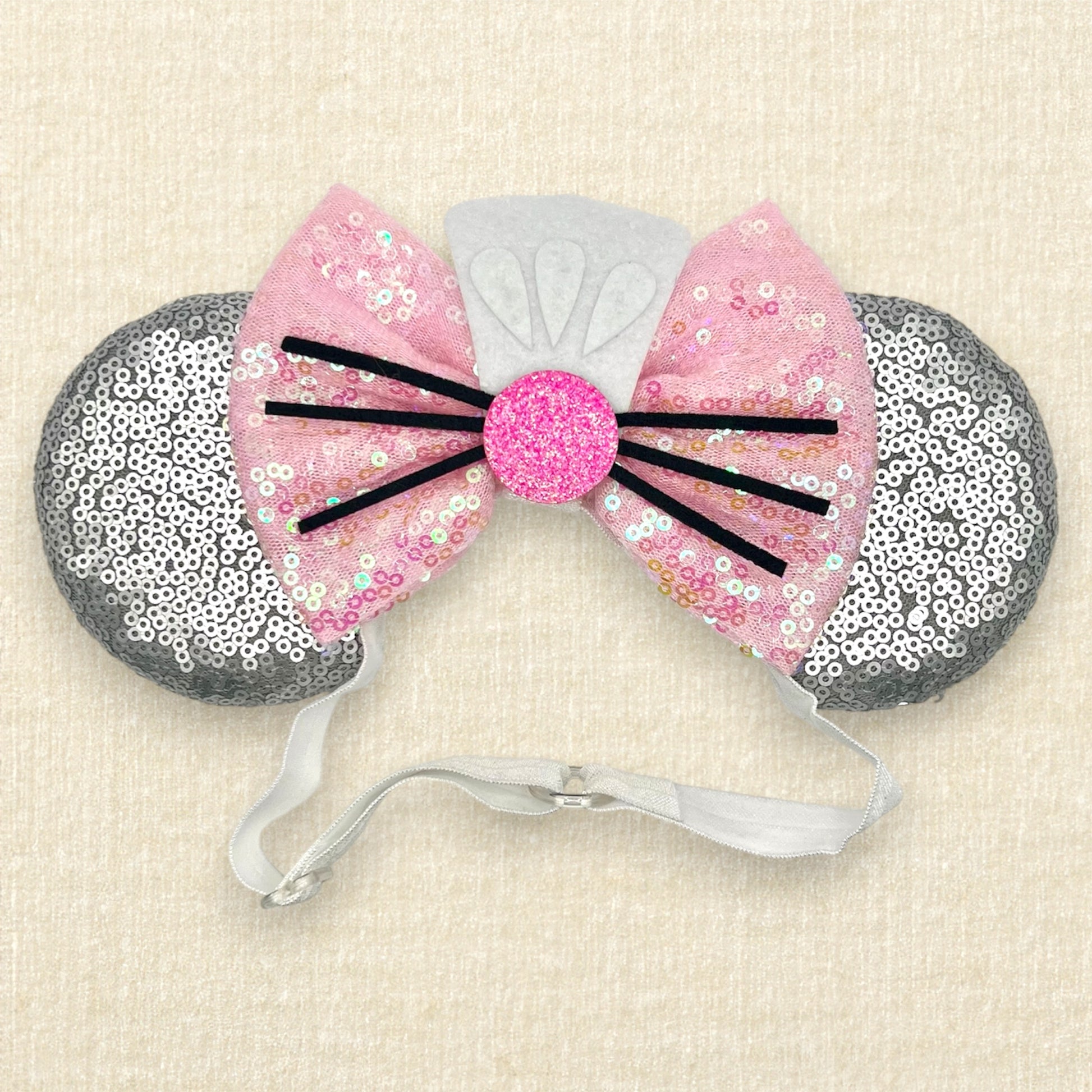 Silver mouse ears with pink sequin bow, mini white chef's hat, and pink glitter mouse nose with whiskers on an elastic headband