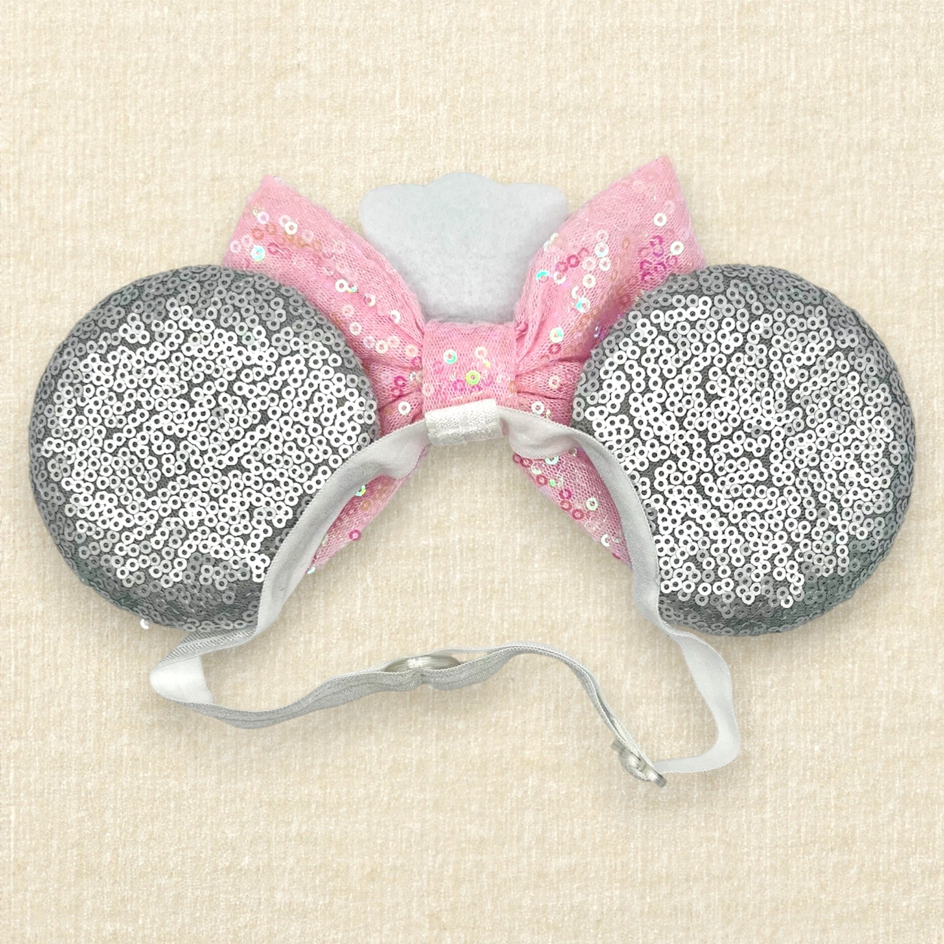 Silver mouse ears with pink sequin bow, mini white chef's hat, and pink glitter mouse nose with whiskers on an elastic headband (back view)