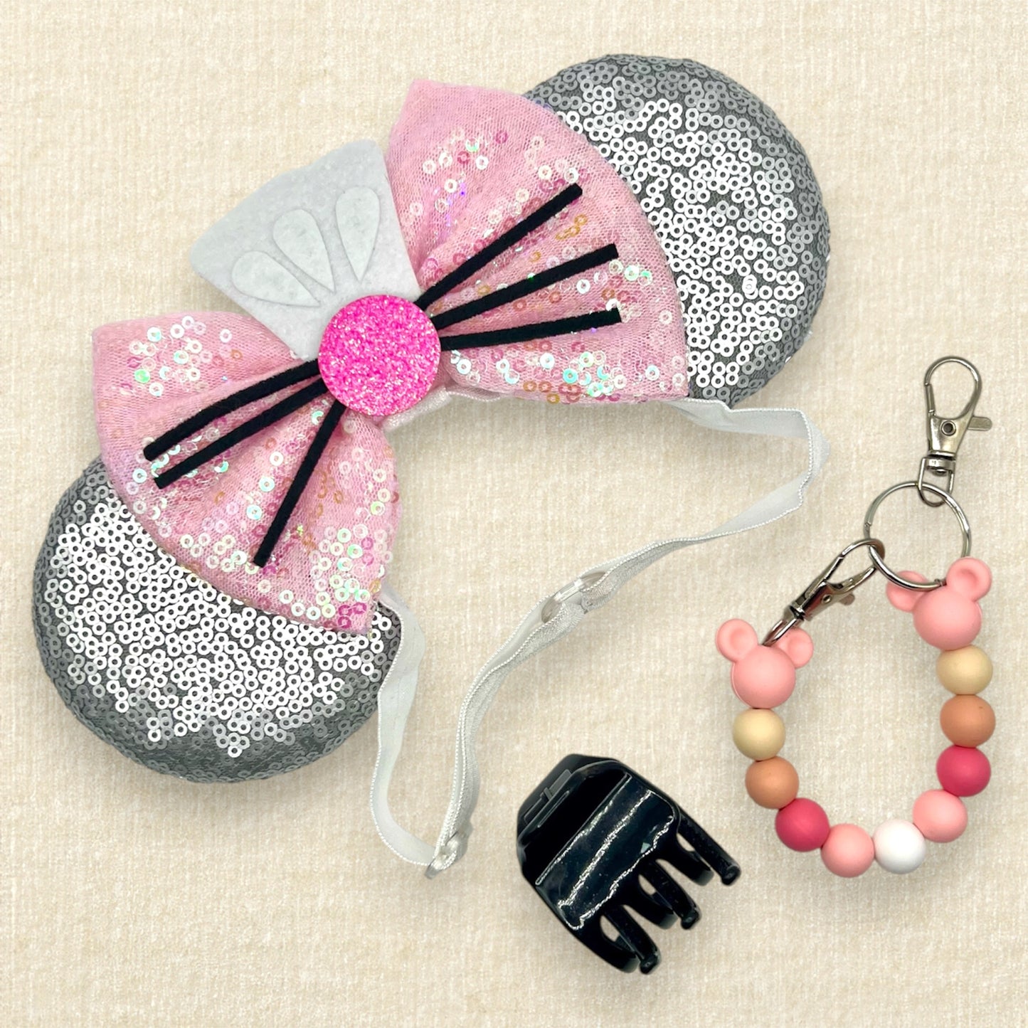 Silver mouse ears with pink sequin bow, mini white chef's hat, and pink glitter mouse nose with whiskers on an elastic headband; black claw clip; pink beaded mouse ears holder clip