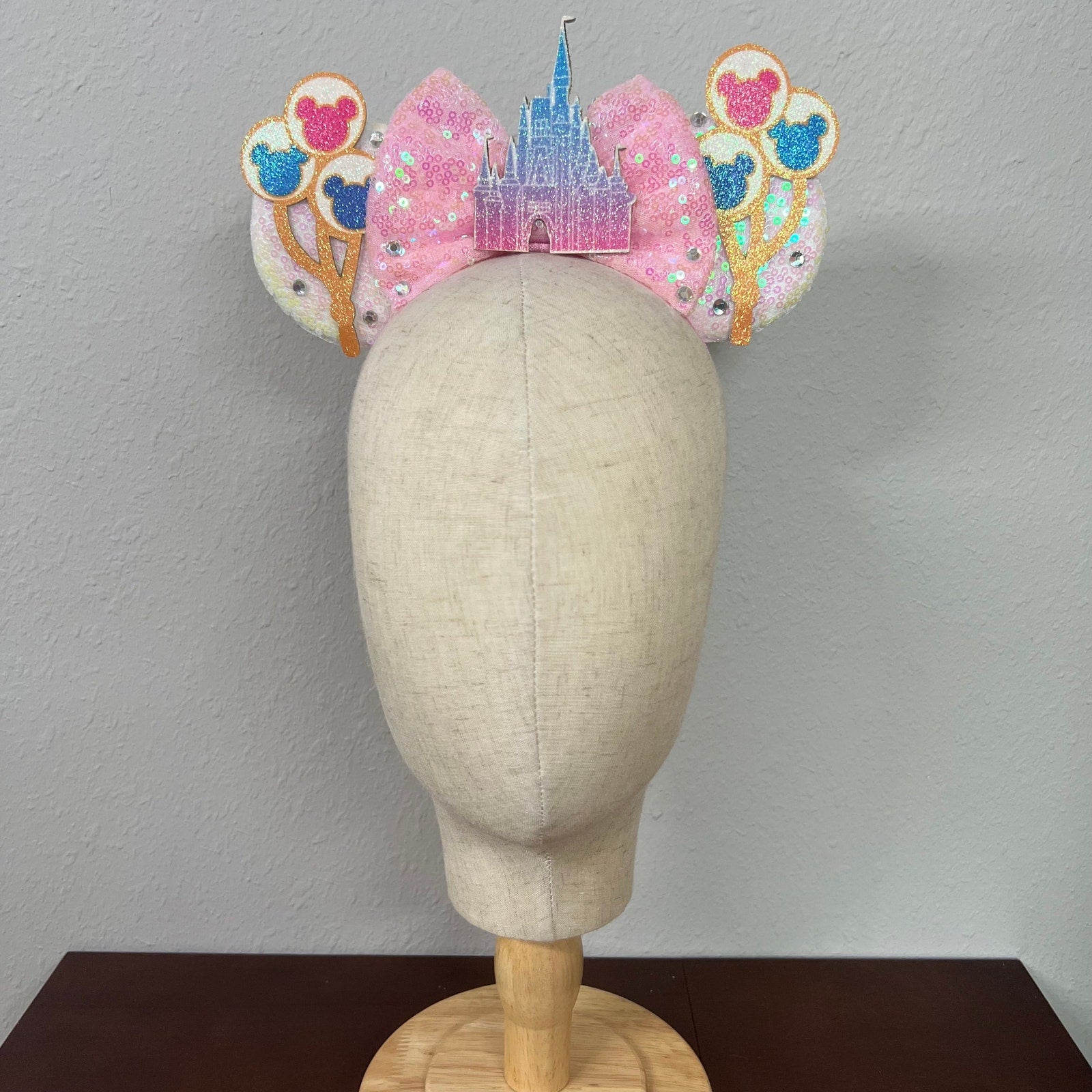 Decorative headband with castle and balloons design on a mannequin head against a plain background