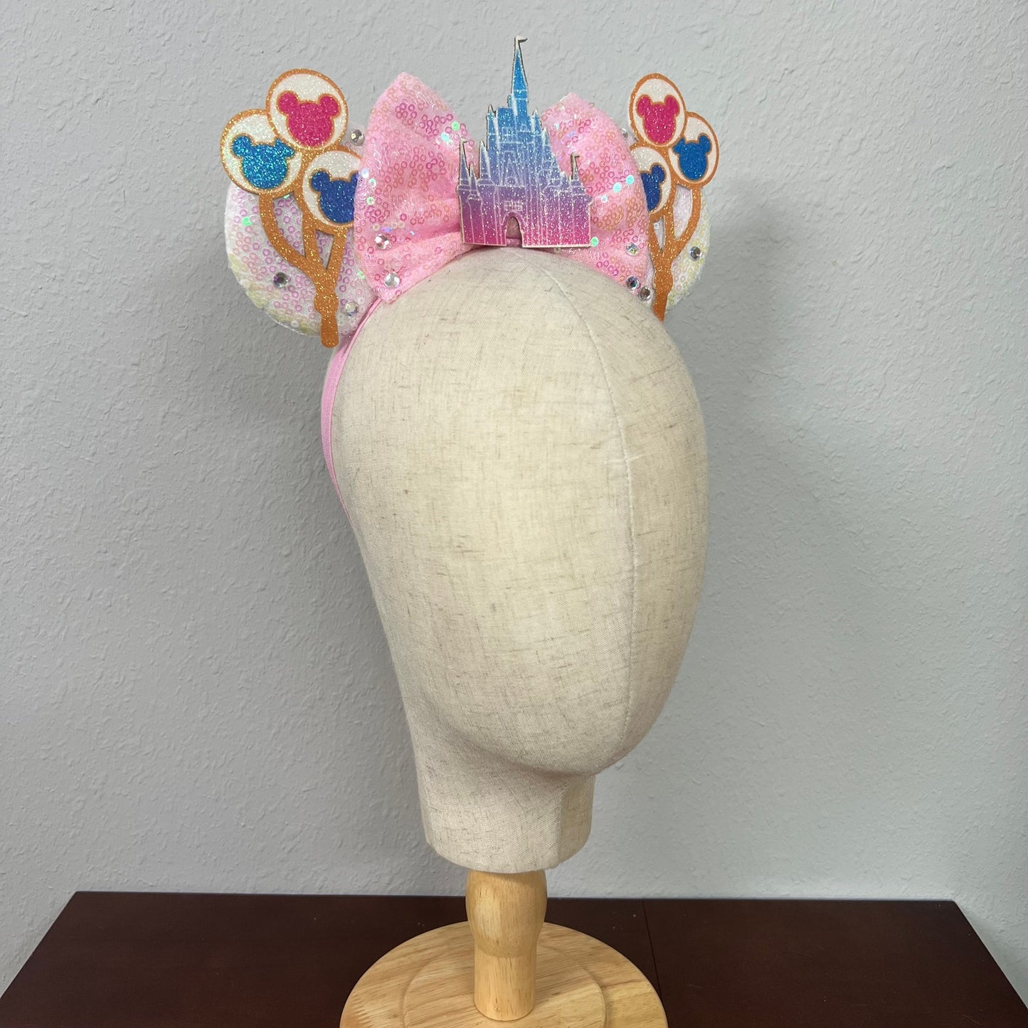 Decorative headband with castle and balloons design on a mannequin head against a plain background