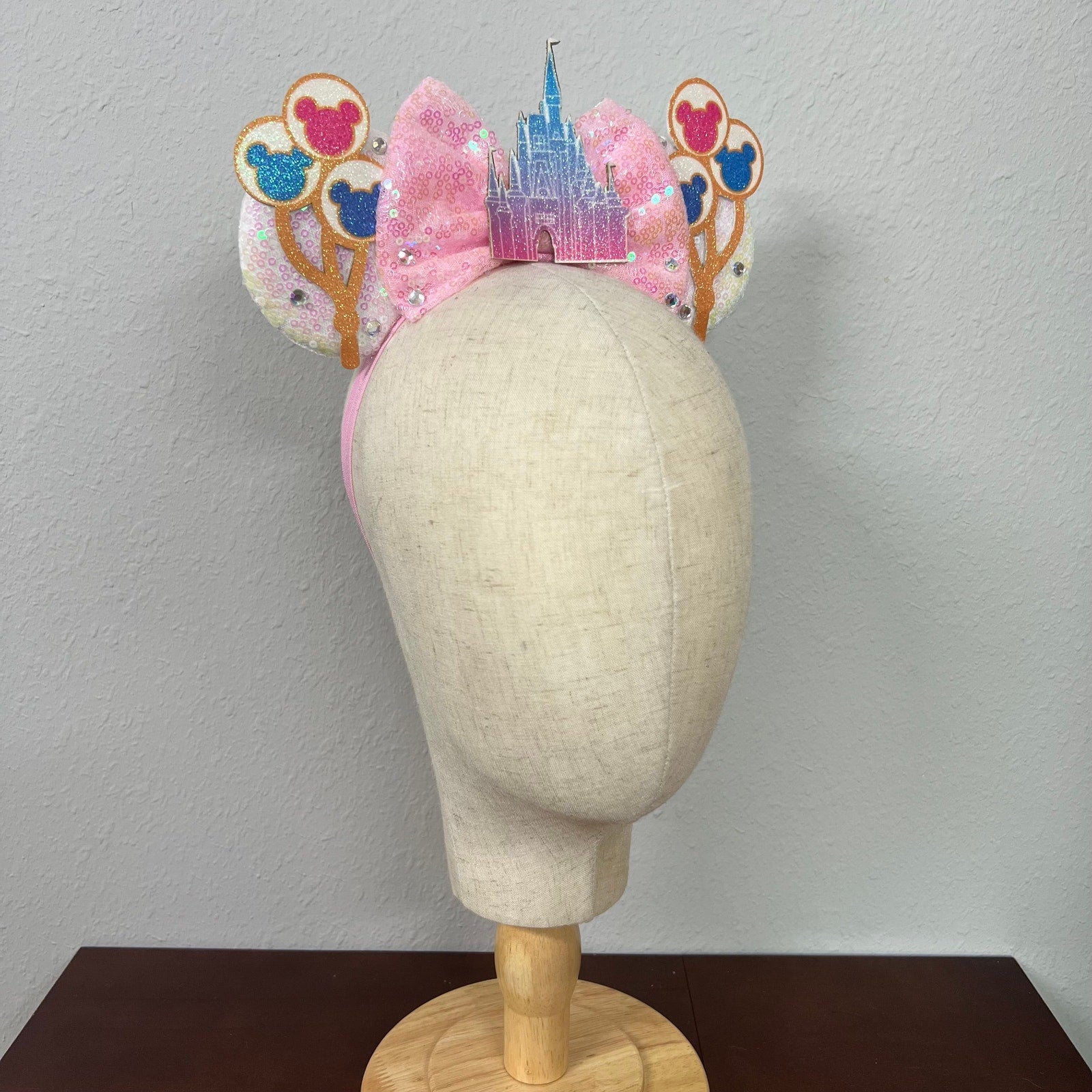Decorative headband with castle and balloons design on a mannequin head against a plain background