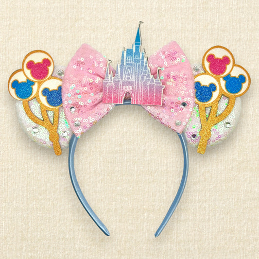 White sequin mouse ears with colorful mouse balloons and a pink bow with pastel pink and blue castle centerpiece