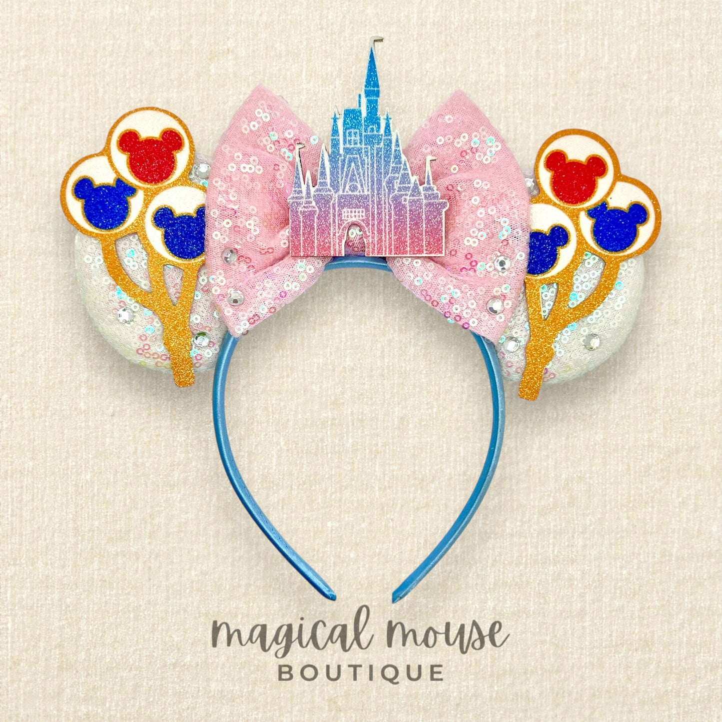 Disney-themed headband with castle design and balloons on a beige background