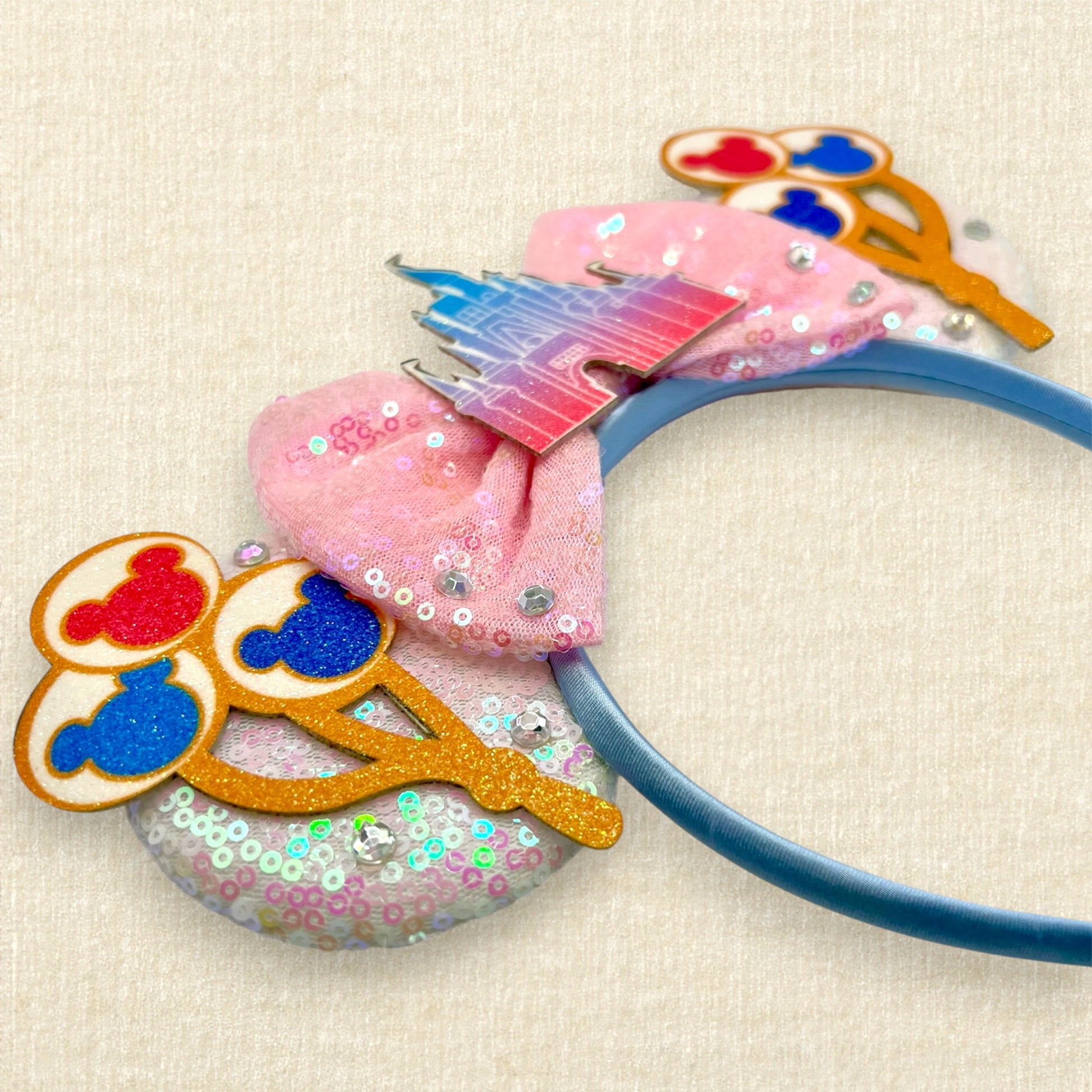 White sequin mouse ears with colorful mouse balloons and a pink bow with pastel pink and blue castle centerpiece