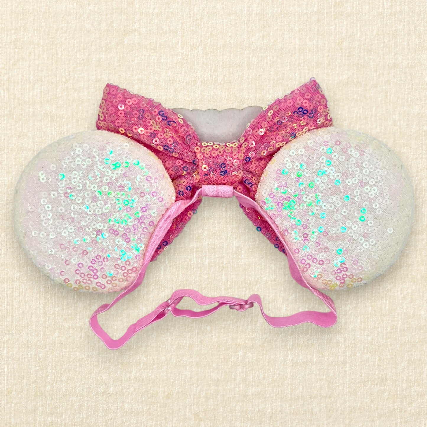 Iridescent white mouse ears with colorful mouse-shaped pearls, pink sequin bow, and glitter 'Birthday Girl' text centerpiece on an elastic headband (back view)