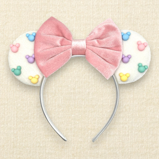 White velvet mouse ears with colorful Mickey pearls and pink velvet bow